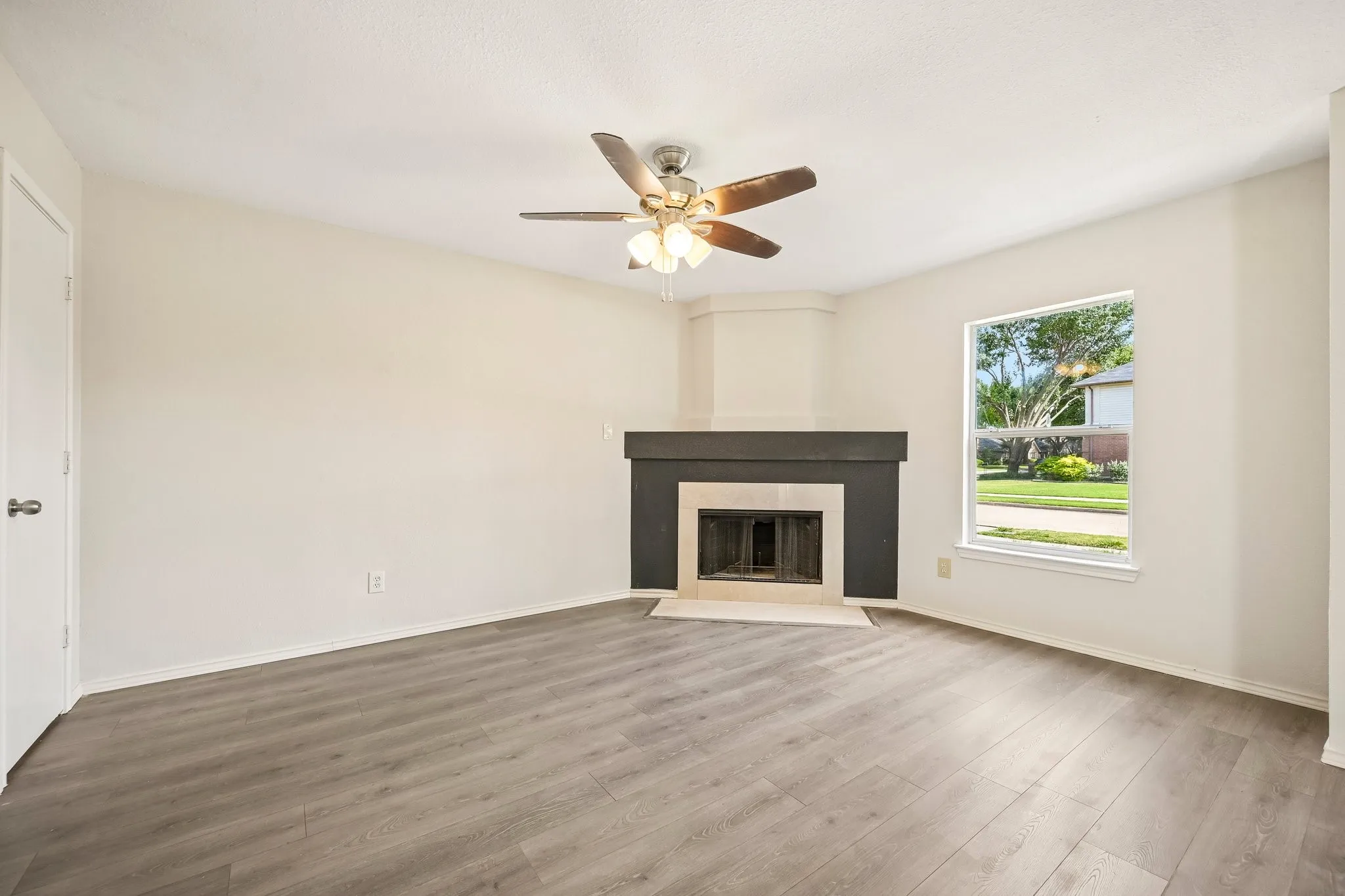 Living area featuring a corner fireplace with a dark mantel, light-toned walls, and wood-finish flooring
