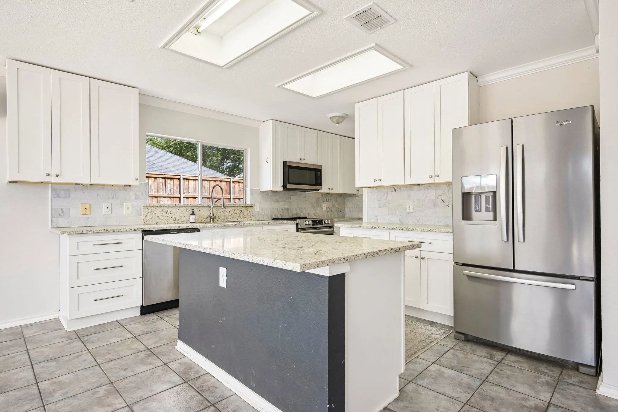 Kitchen featuring white cabinetry, granite countertops, a central island, stainless steel appliances, and tile flooring