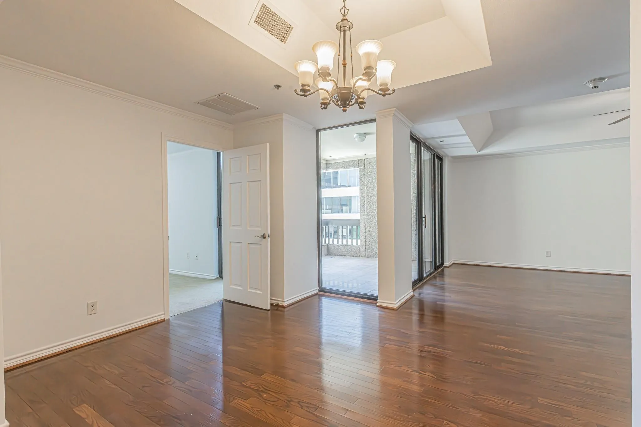 Spacious interior featuring wood-finish flooring, a tray ceiling with a chandelier, and crown molding