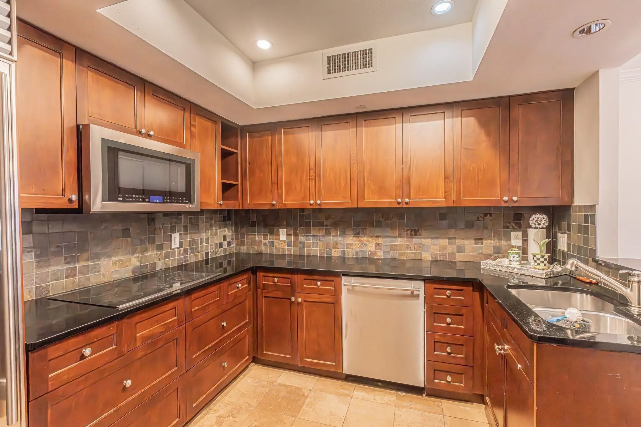 U-shaped kitchen with wood cabinetry and dark countertops