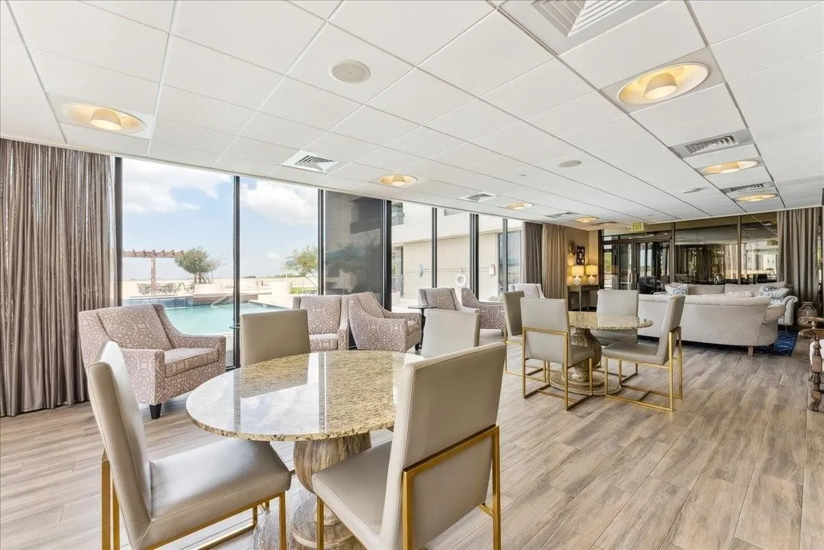 Expansive common area featuring floor-to-ceiling windows, wood-finish flooring, and recessed ceiling lighting