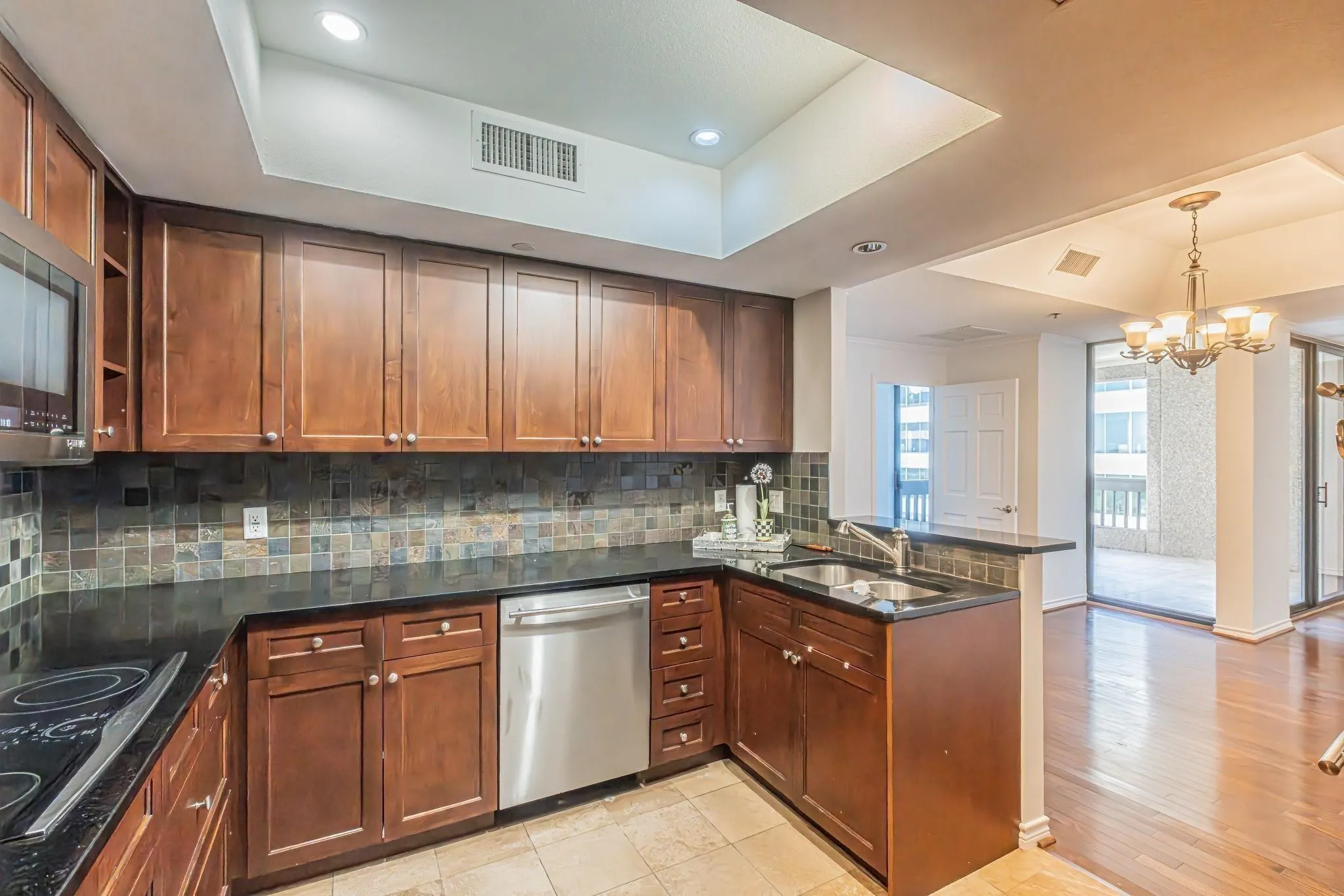 Kitchen featuring wood cabinetry, dark countertops, a tile backsplash, and stainless steel appliances