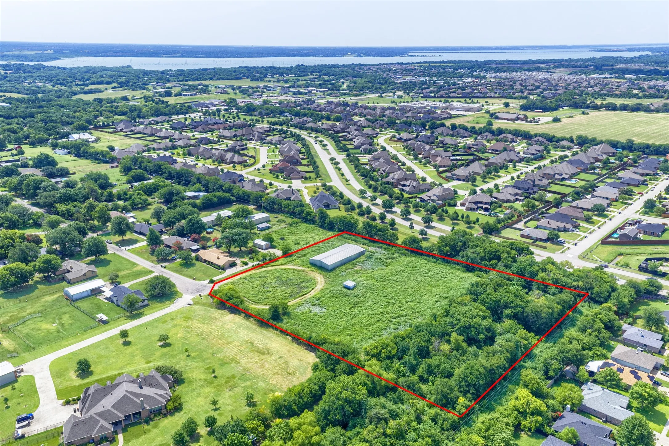 Expansive undeveloped land parcel outlined in red, featuring a mix of open grassy areas and mature tree clusters