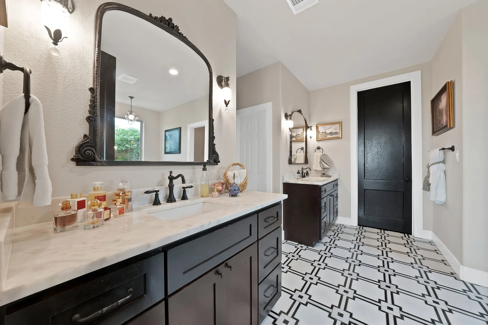 Bathroom with patterned floor tile, dark wood-finish vanity with white countertop and integrated sink, and an ornate framed mirror
