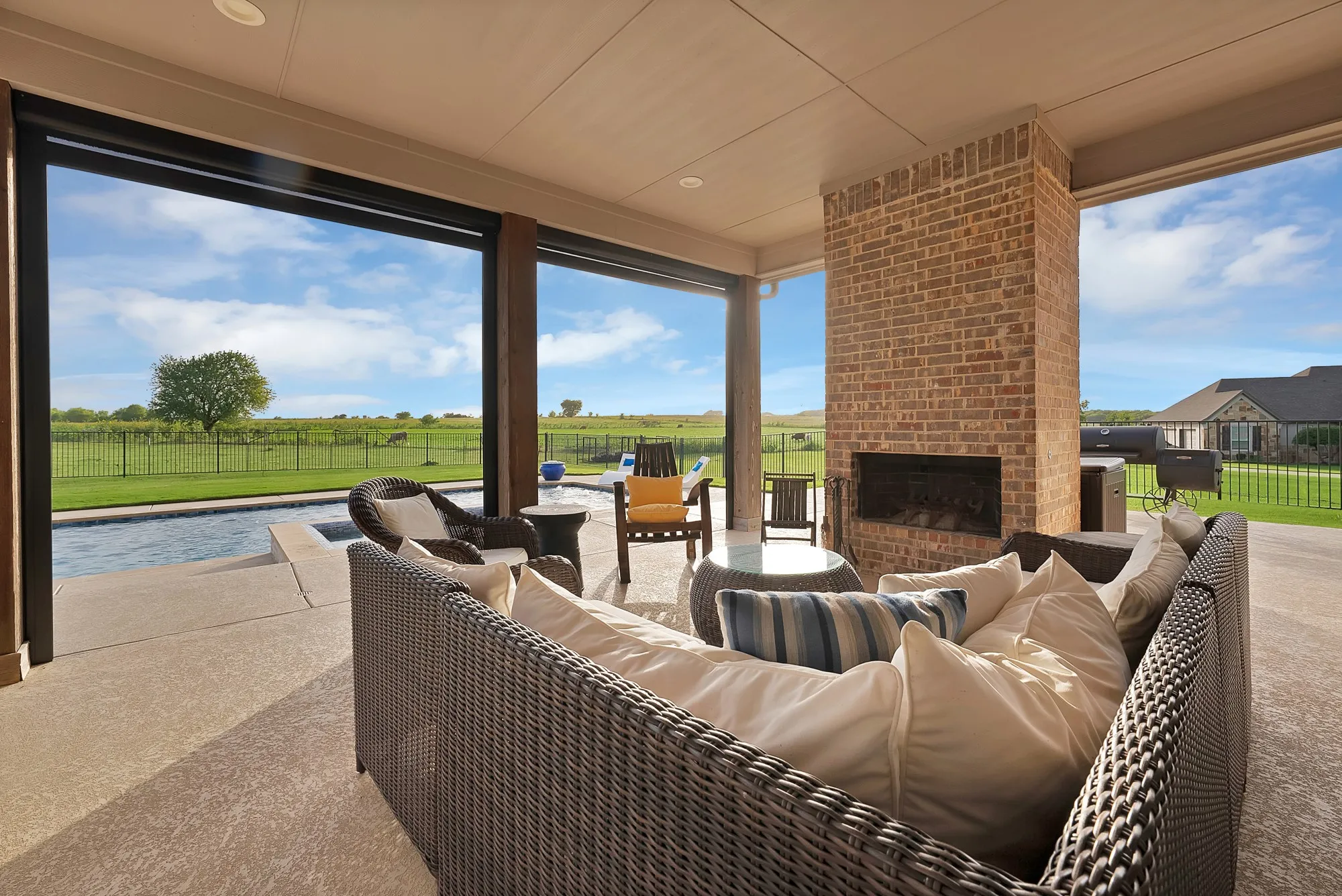 Covered patio featuring a brick fireplace, concrete flooring, and a recessed ceiling