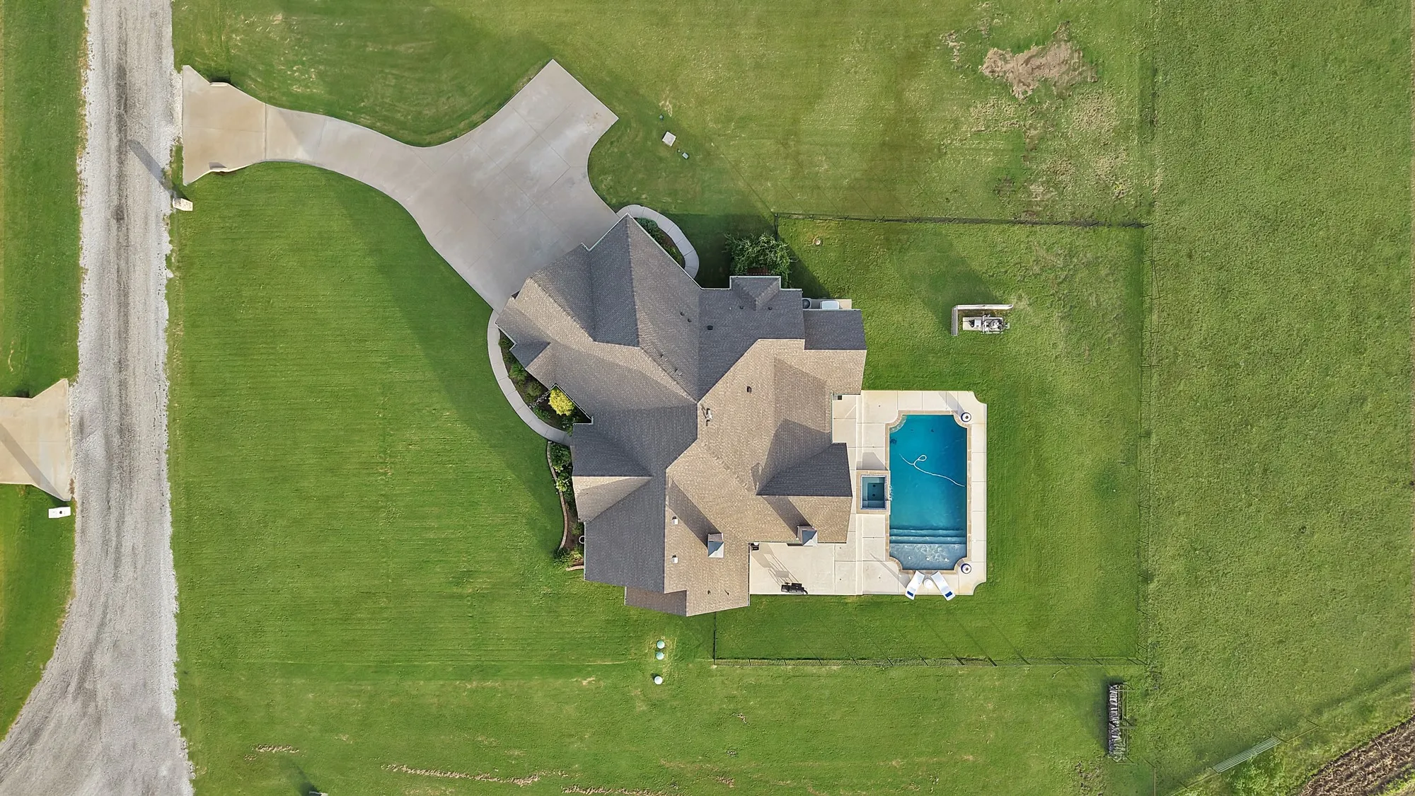 Expansive property featuring a multi-gabled roofline, concrete driveways, an inground pool with a spa, and extensive green space