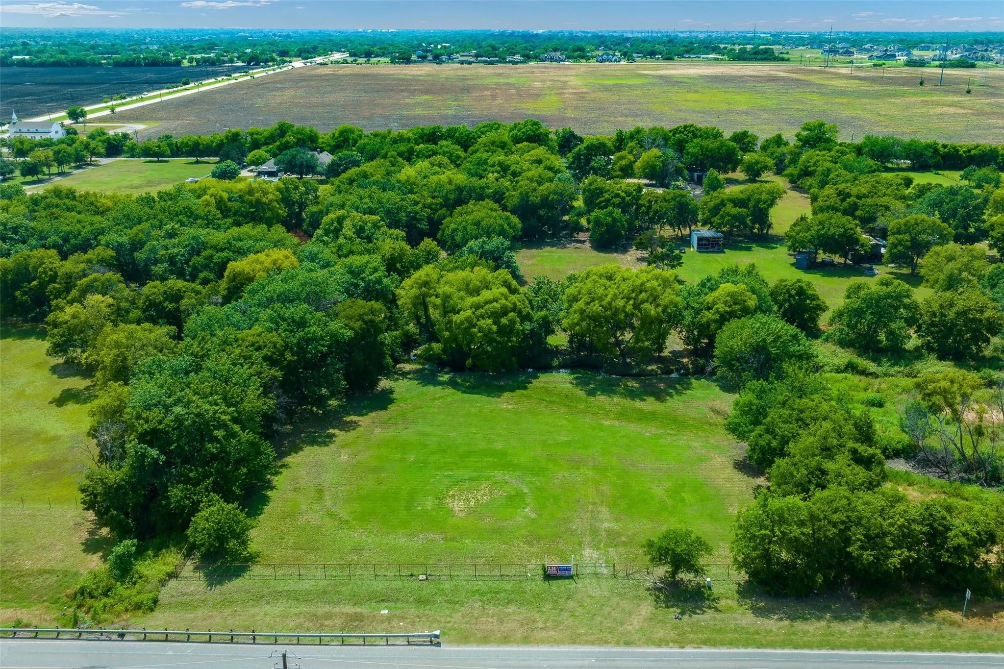 Expansive parcel featuring a large open field, mature trees, and a tree-lined perimeter