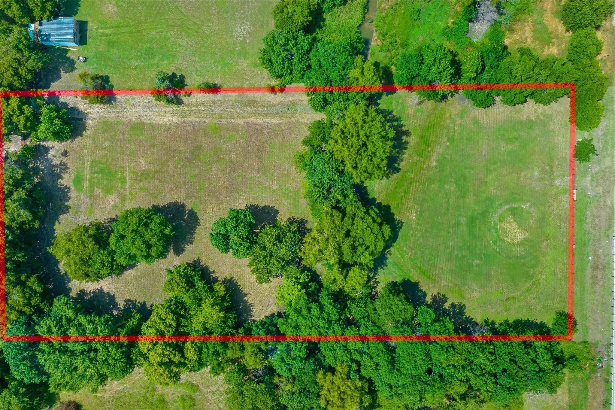 Expansive land parcel featuring a mix of open grassy areas and mature trees