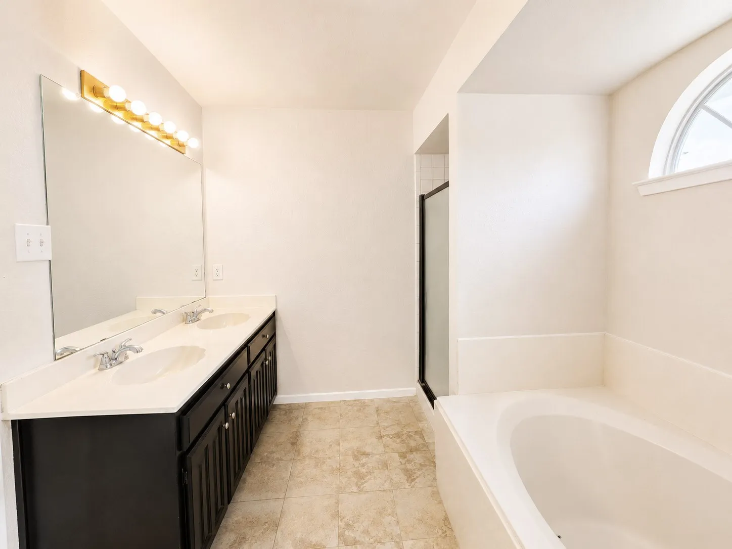 Double vanity with dark wood-finish cabinetry, two undermount sinks, and a light-toned countertop