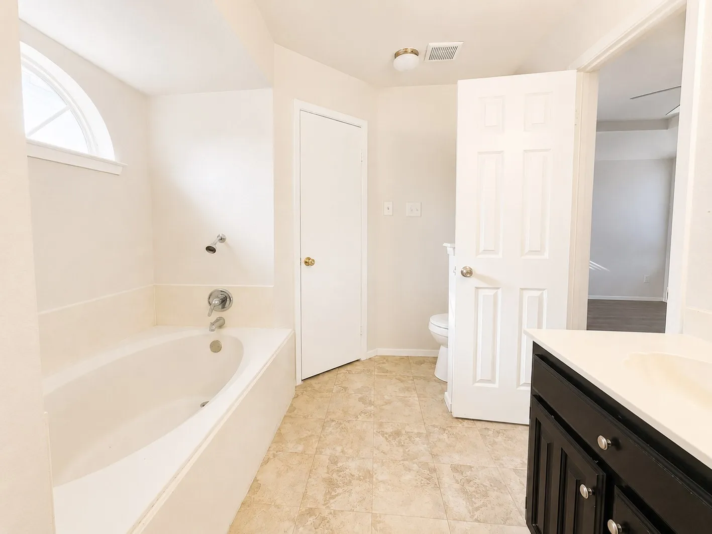 Soaking tub with chrome fixtures and an arched window