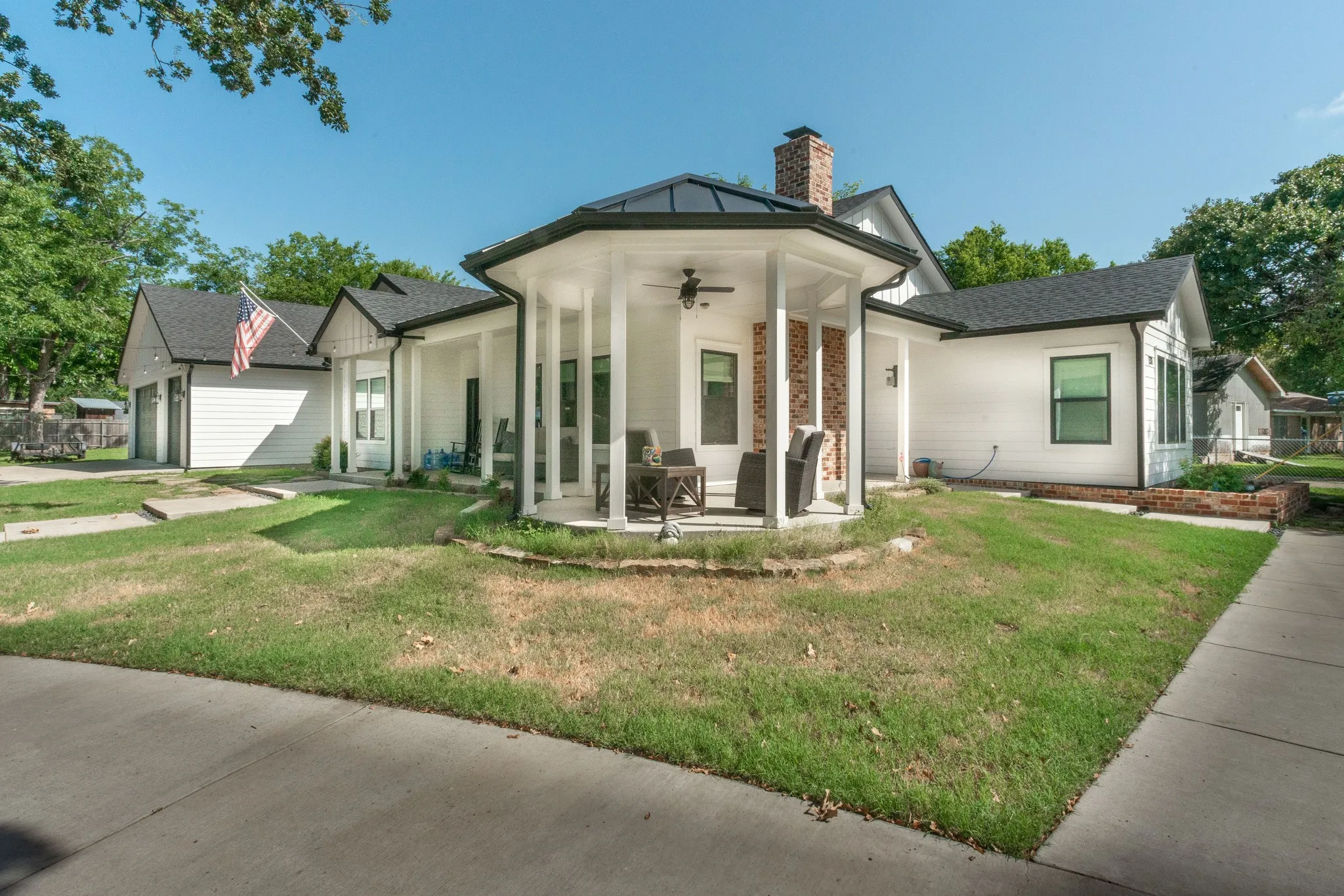 White siding exterior featuring a covered hexagonal porch with column supports and a ceiling fan