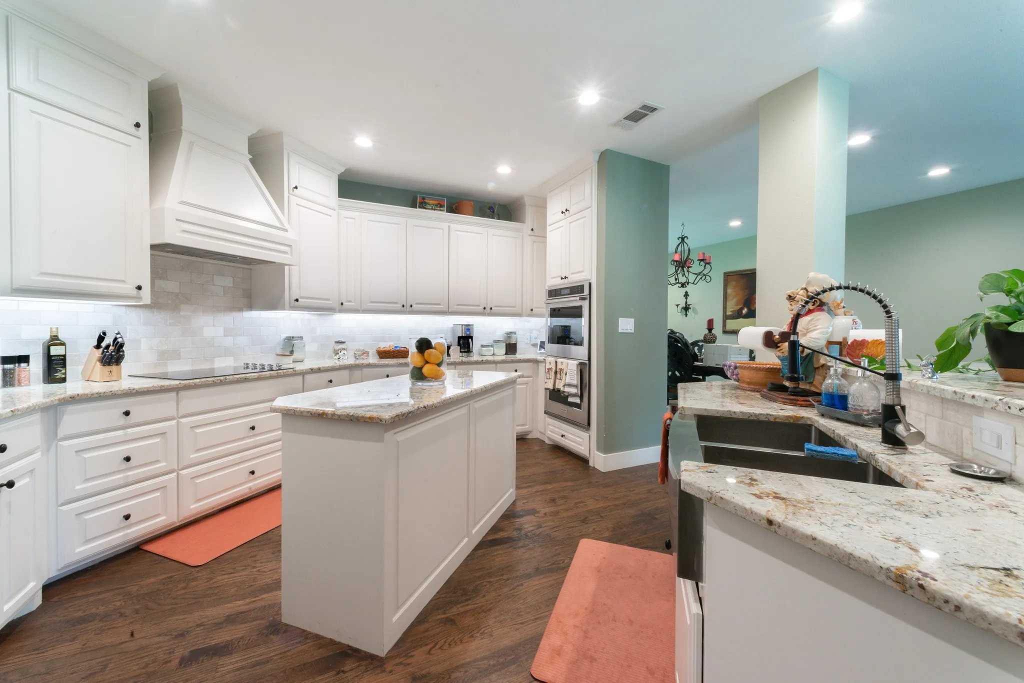 Kitchen featuring white cabinetry, granite countertops, a central island, wood-finish flooring, and recessed lighting