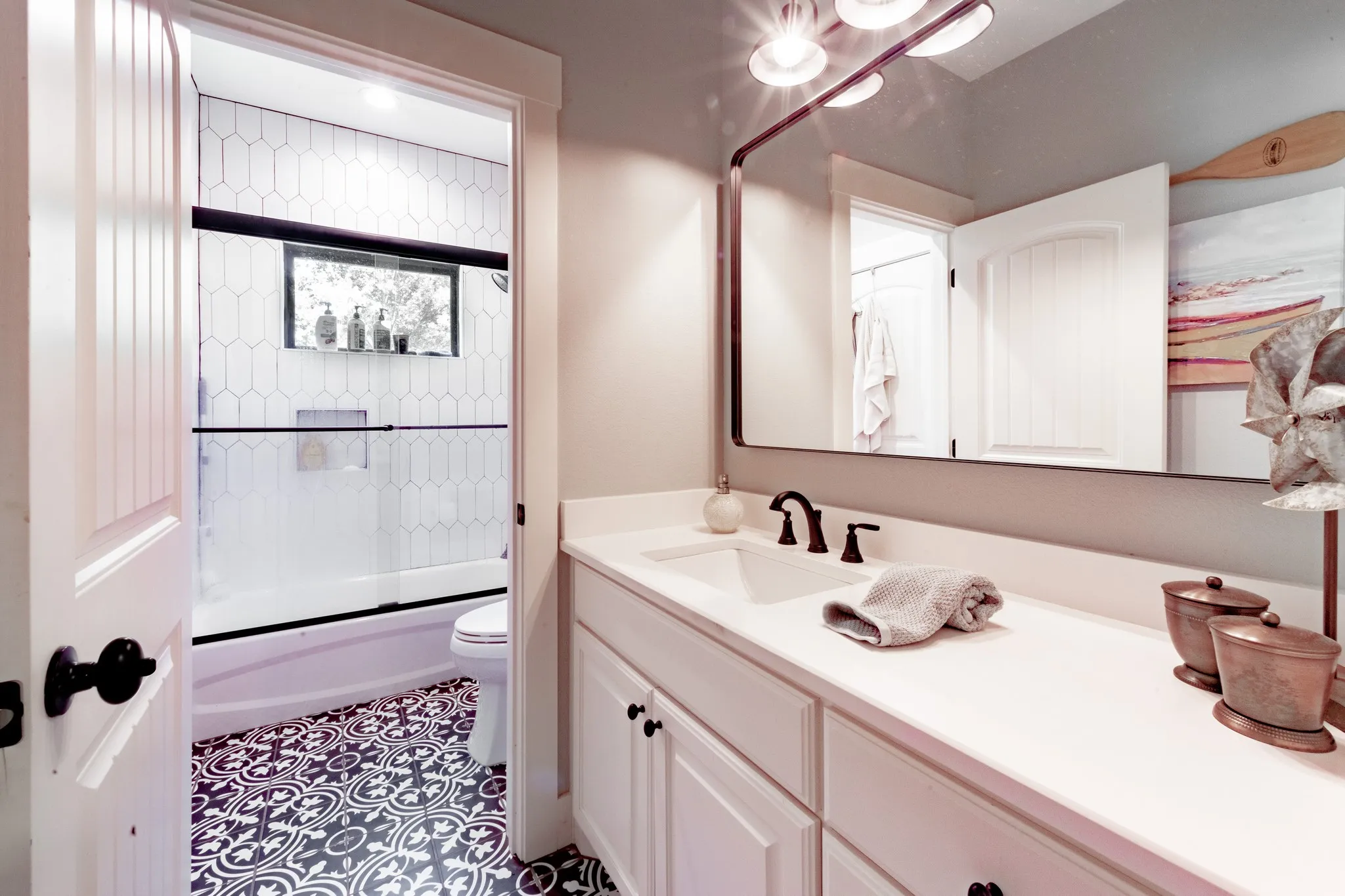 Bathroom featuring a white vanity with integrated sink, black fixtures, and a large wall-mounted mirror