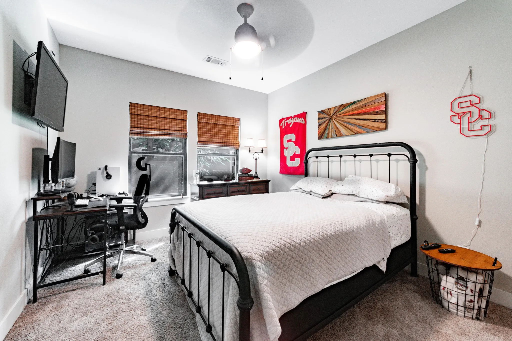 Carpeted room featuring two windows with woven wood blinds, a ceiling fan with integrated lighting, and white baseboards
