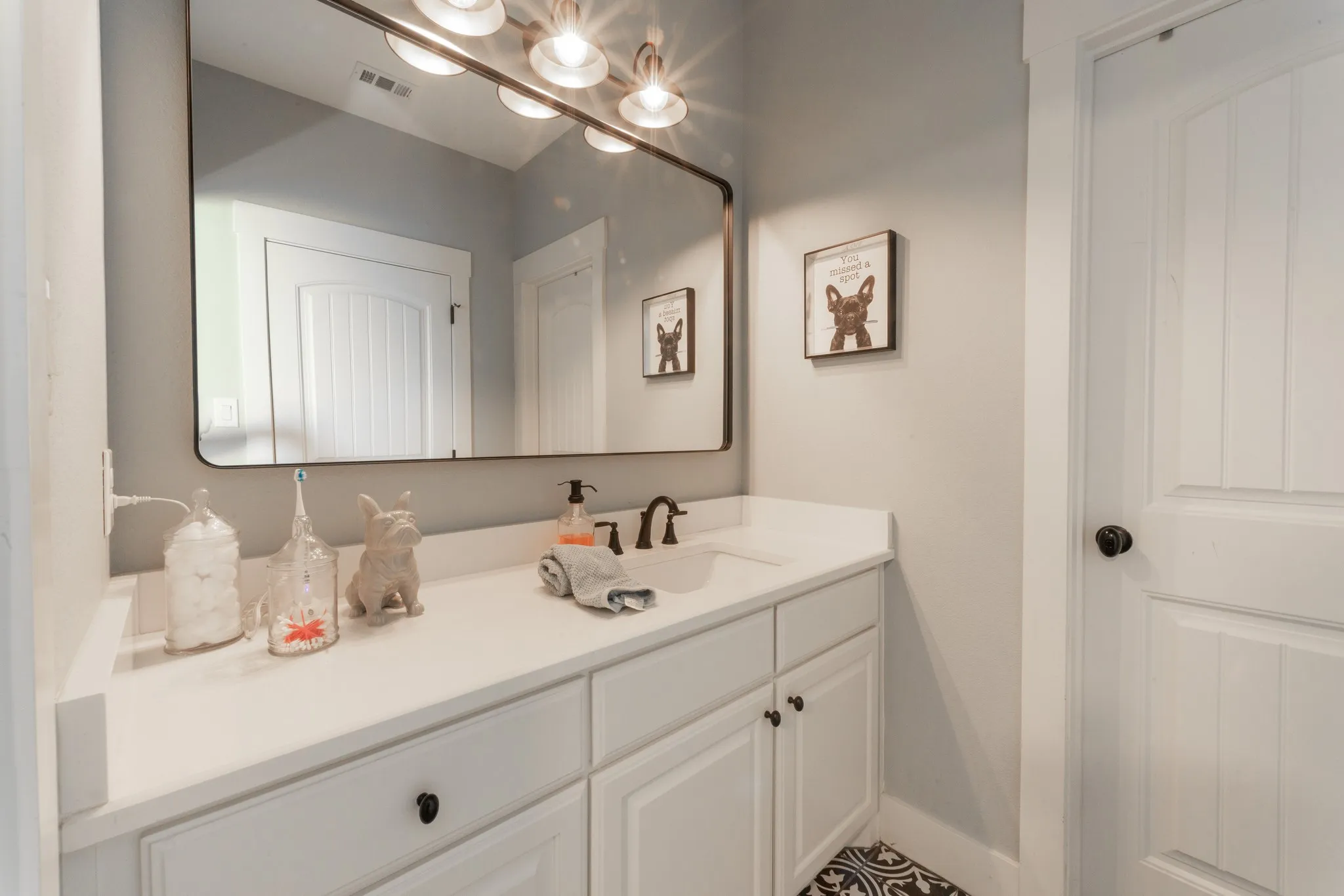 Bathroom vanity featuring a white countertop, undermount sink, and black faucet