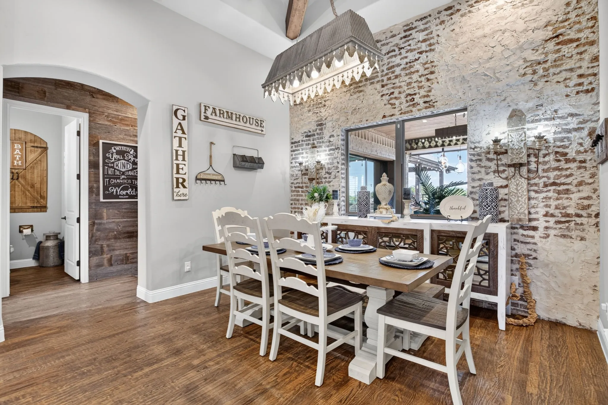 Dining area featuring a distressed brick accent wall and wood-finish flooring