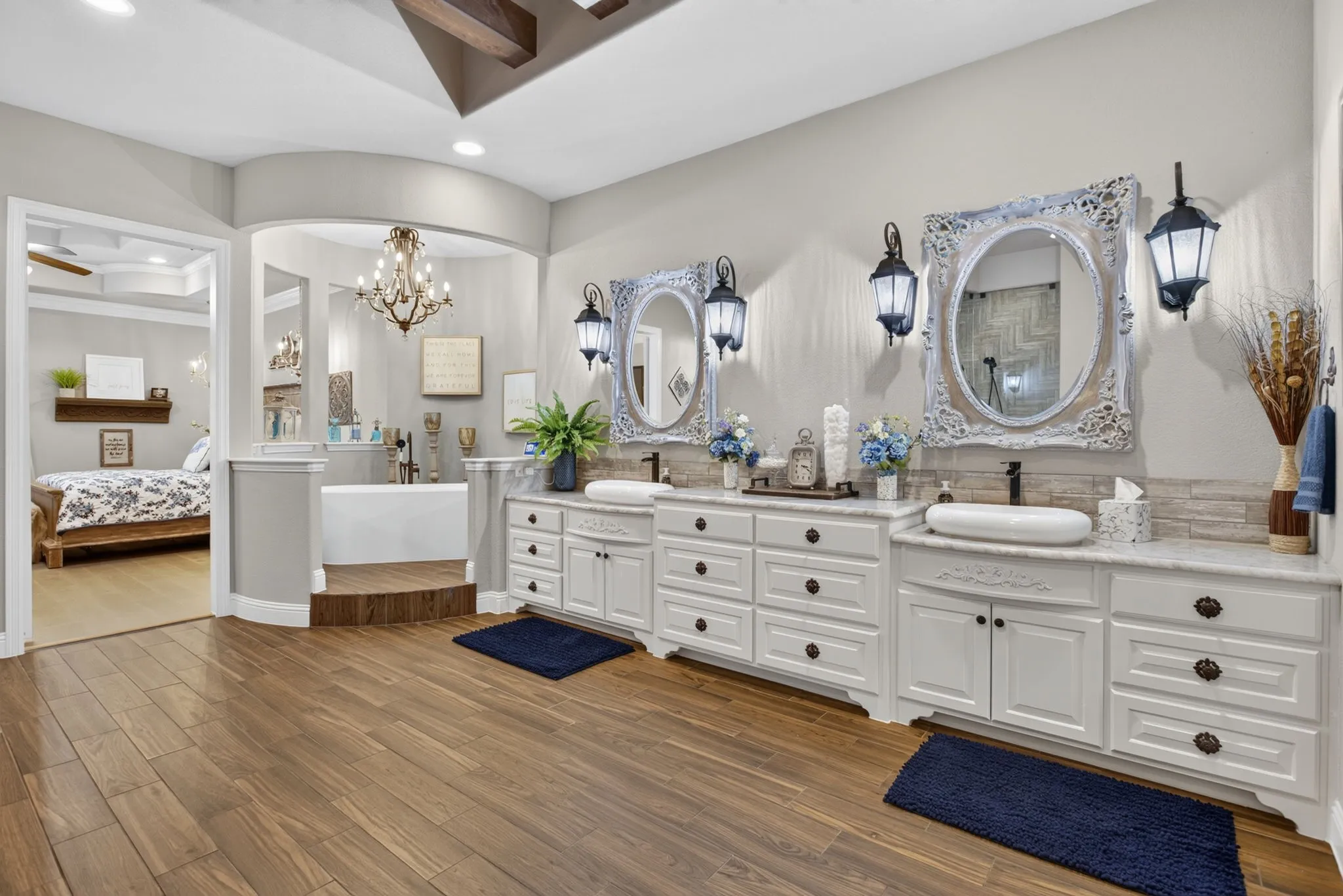 Bathroom featuring wood-finish flooring, dual vanity with white cabinetry, vessel sinks, and light-colored countertops