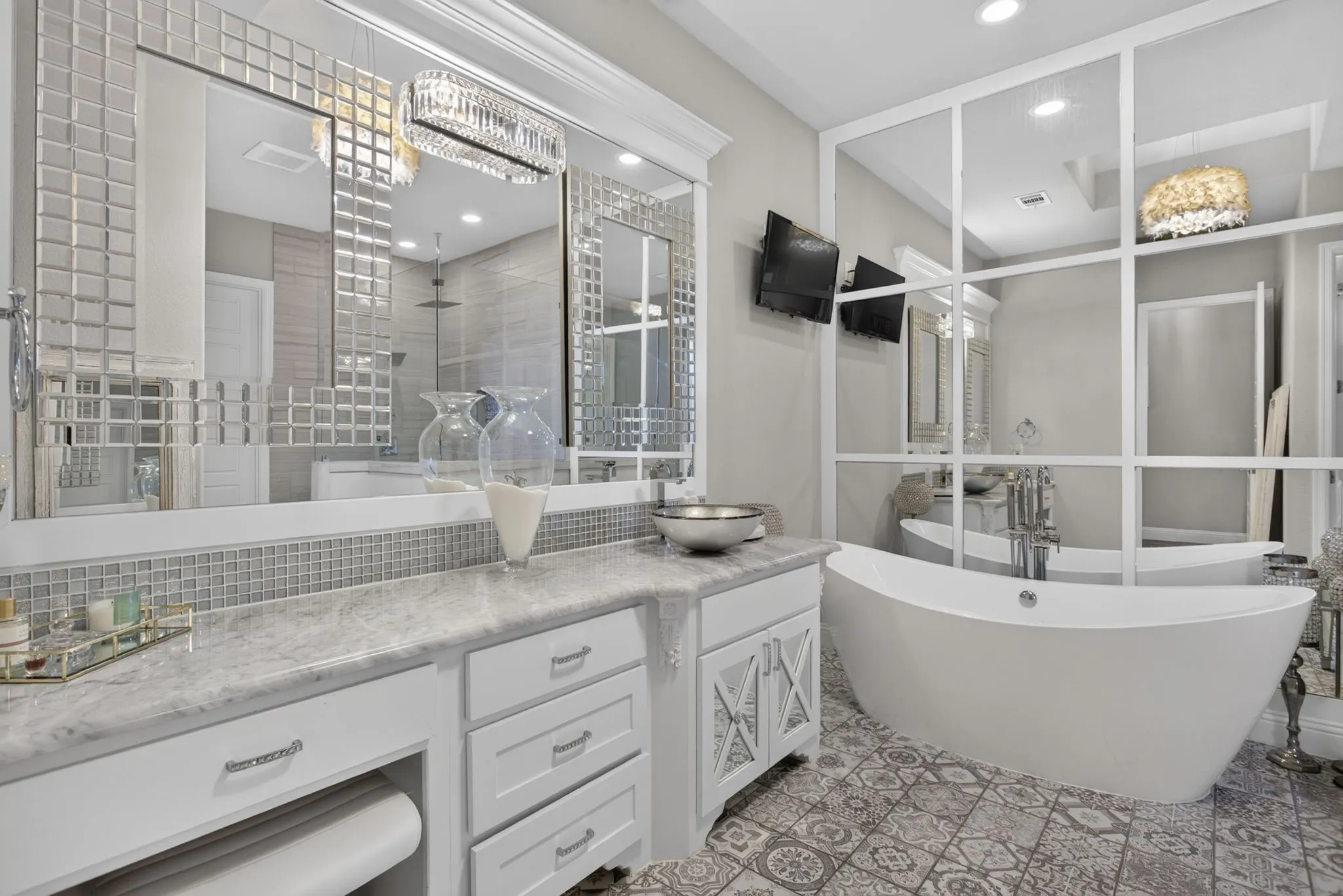 Bathroom featuring a freestanding tub, dual vanity with a vessel sink, patterned tile flooring, and decorative mirrored accents