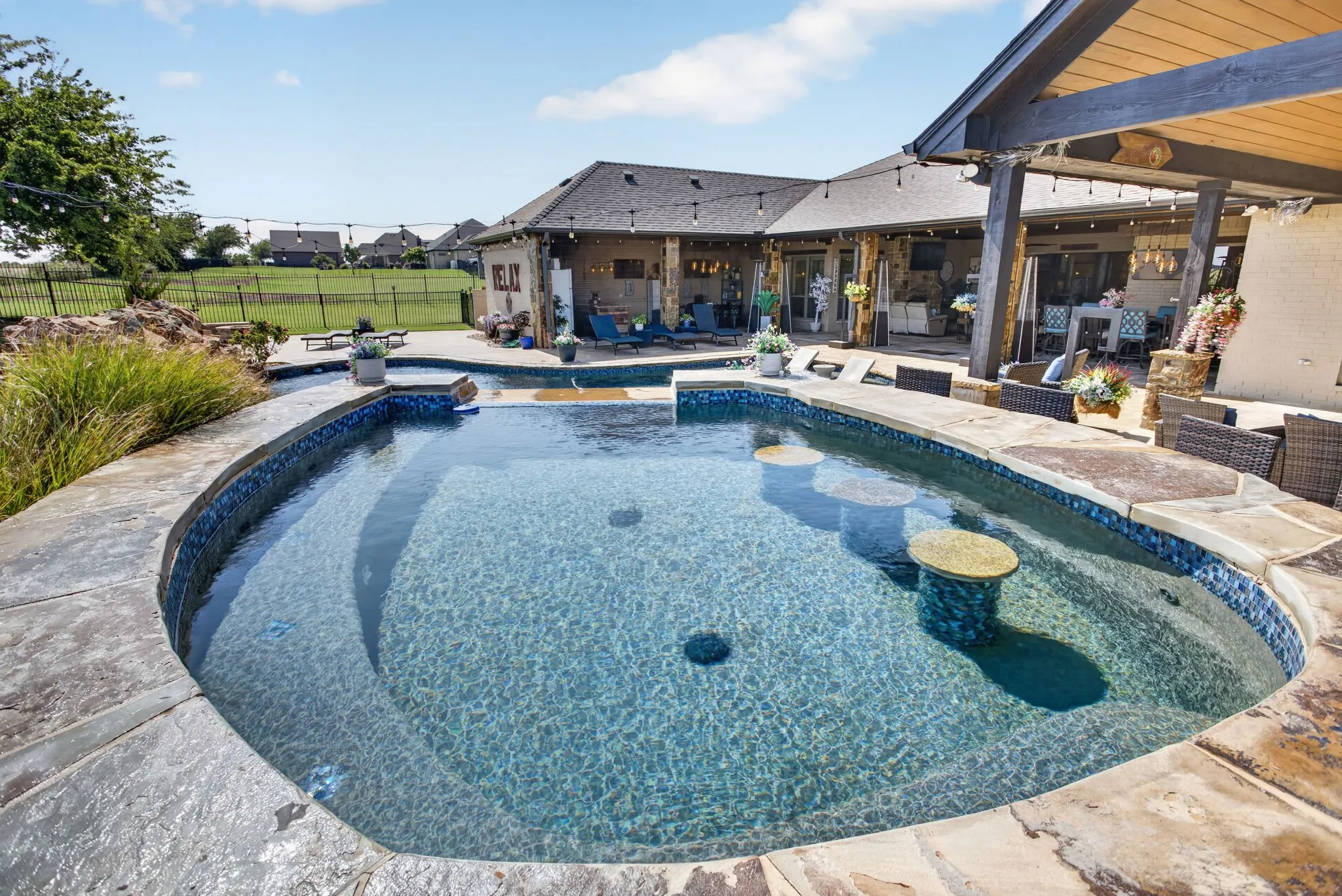 Freeform swimming pool featuring an integrated spa, swim-up bar seating, and stone coping