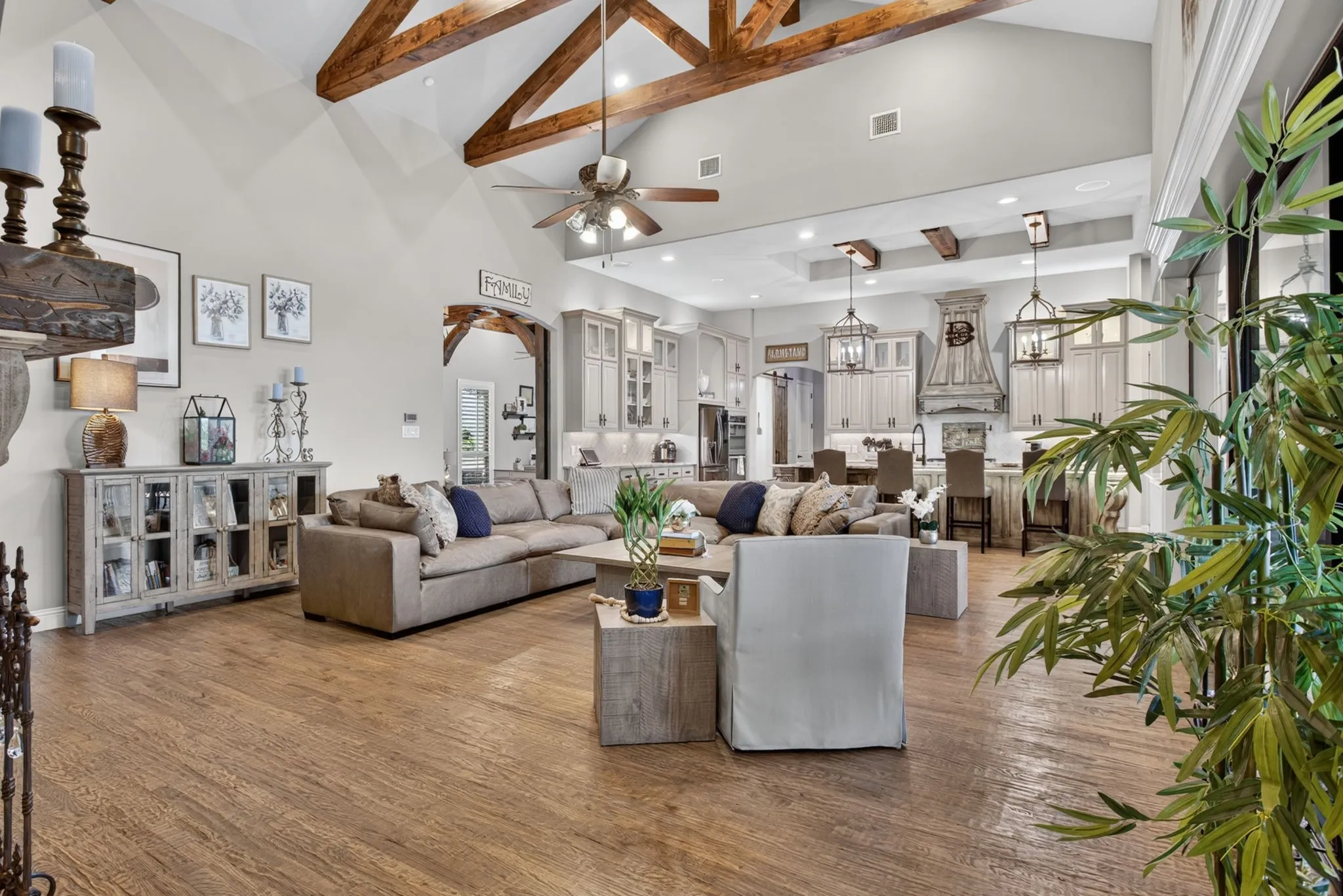 Spacious living area featuring exposed wood ceiling beams, wood-finish flooring, recessed lighting, and an open-concept design to the kitchen