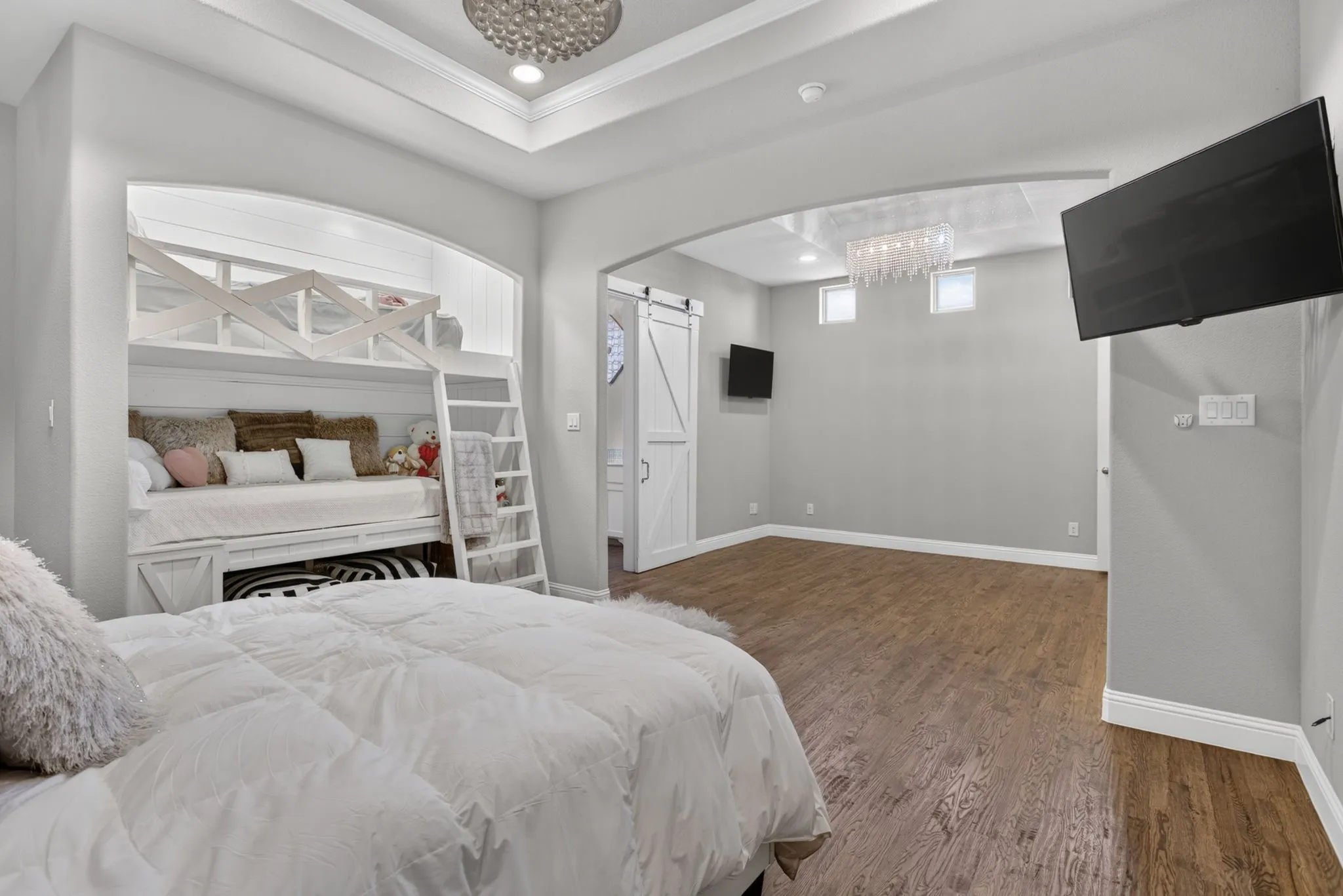 Bedroom 4 is second primary bedroom & has Recessed bunk bed niche with a built-in ladder, wood-finish flooring, tray ceiling, recessed lighting, and a white barn door