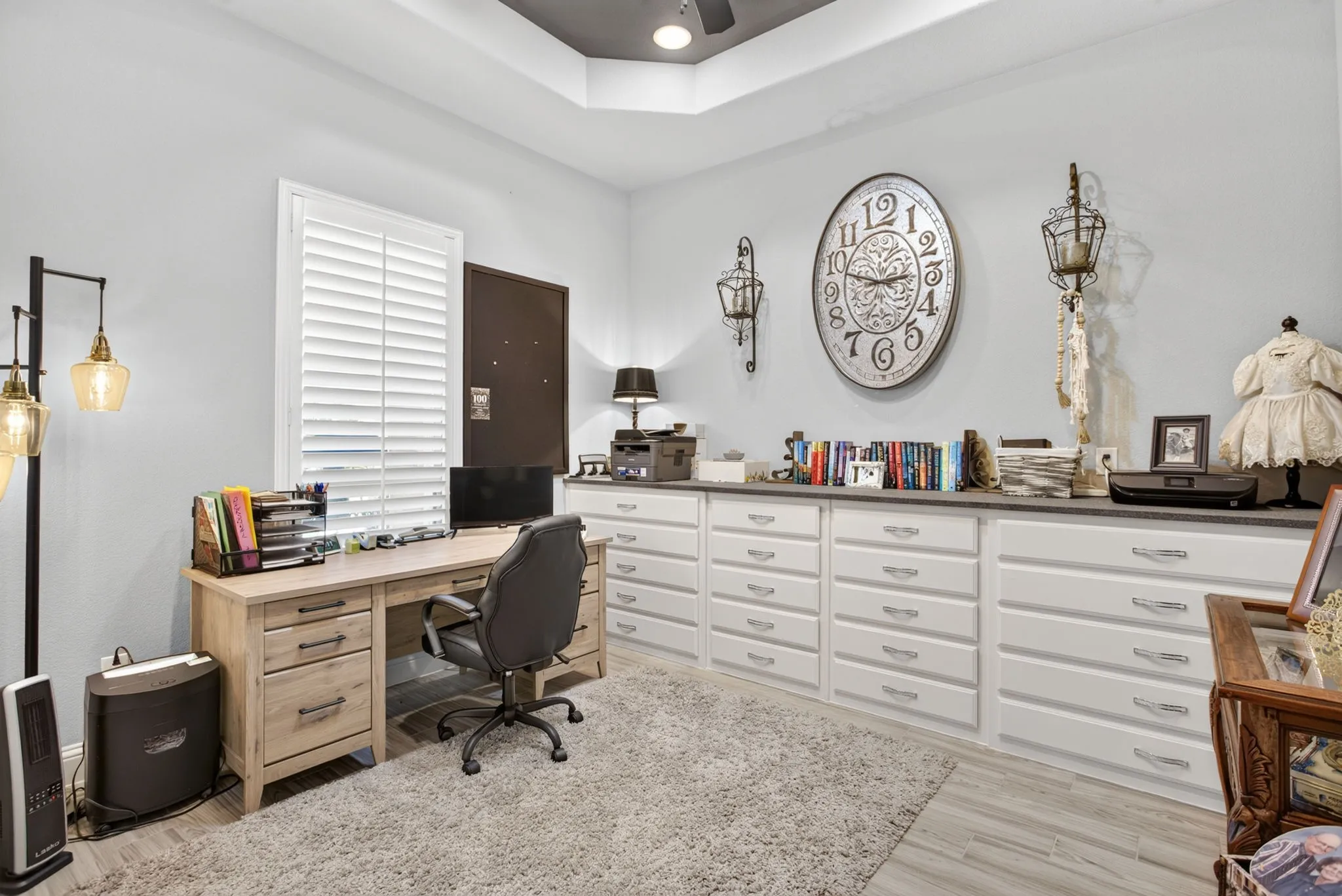 Bedroom #3 featuring extensive built-in cabinetry with white drawer fronts and silver-toned hardware, a light wood-finish desk, and a window with white plantation shutters