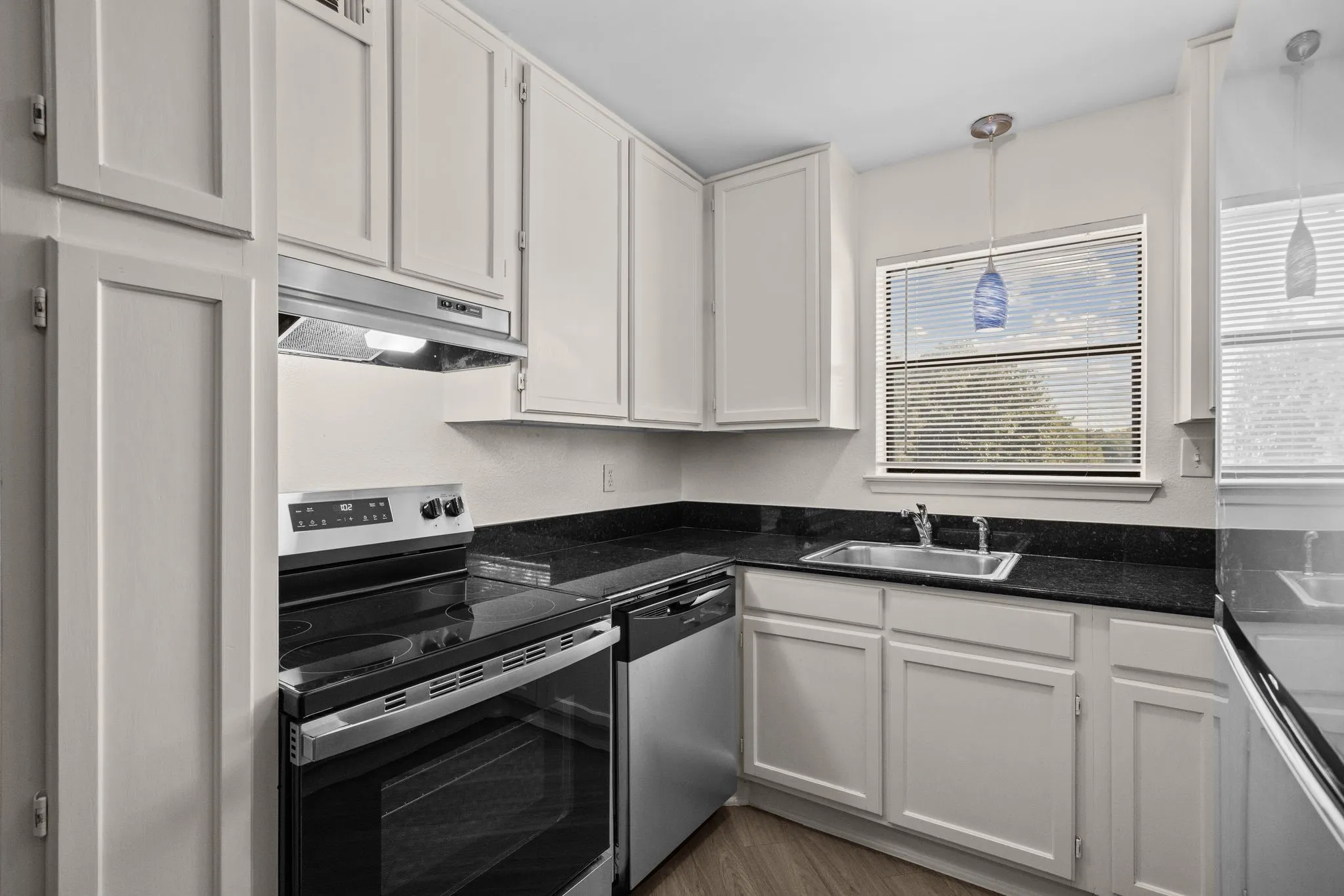 Kitchen featuring white shaker-style cabinetry, dark granite-look countertops, and stainless steel appliances