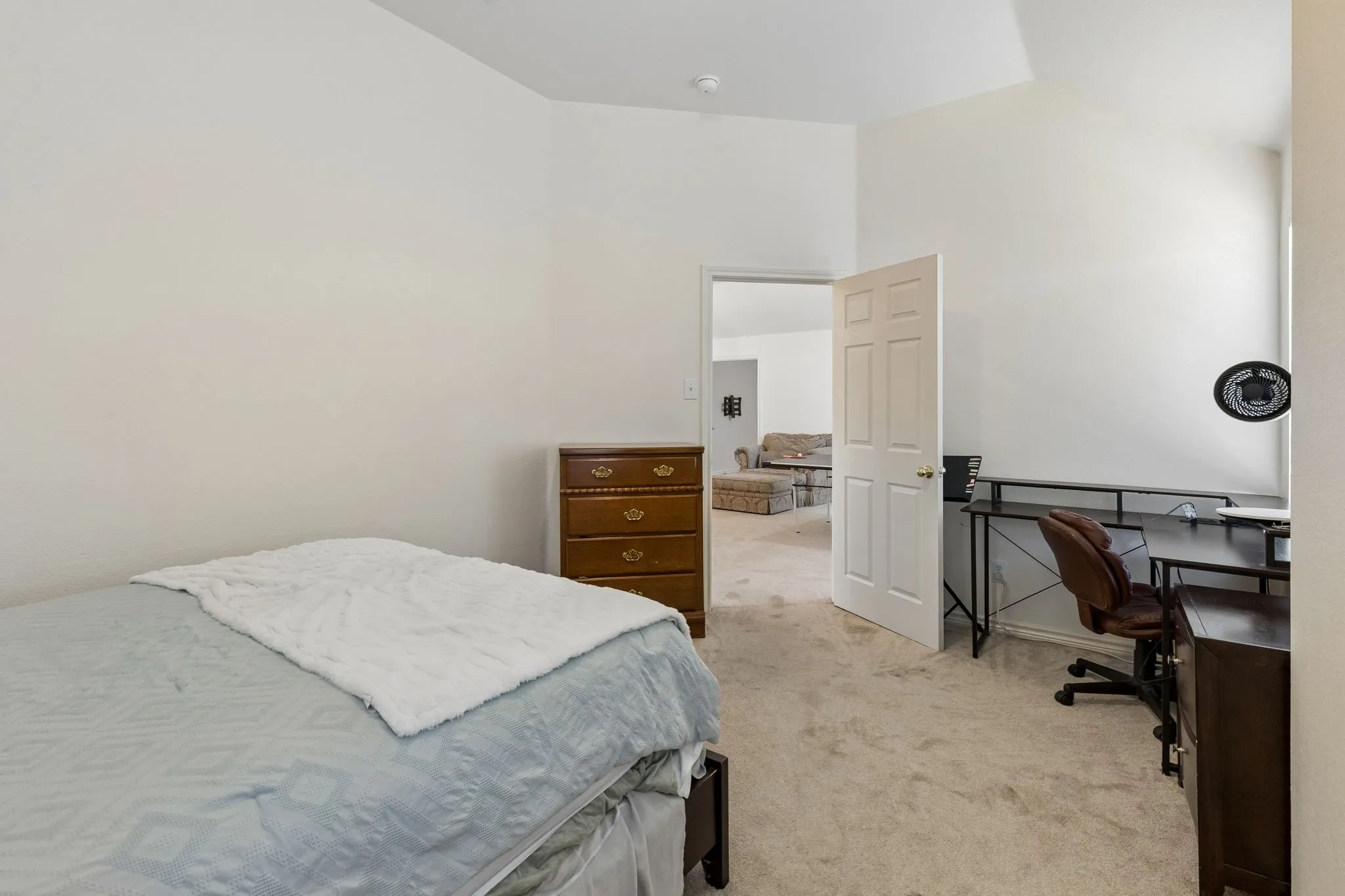 Carpeted room featuring a white paneled door, vaulted ceiling, and light wall paint