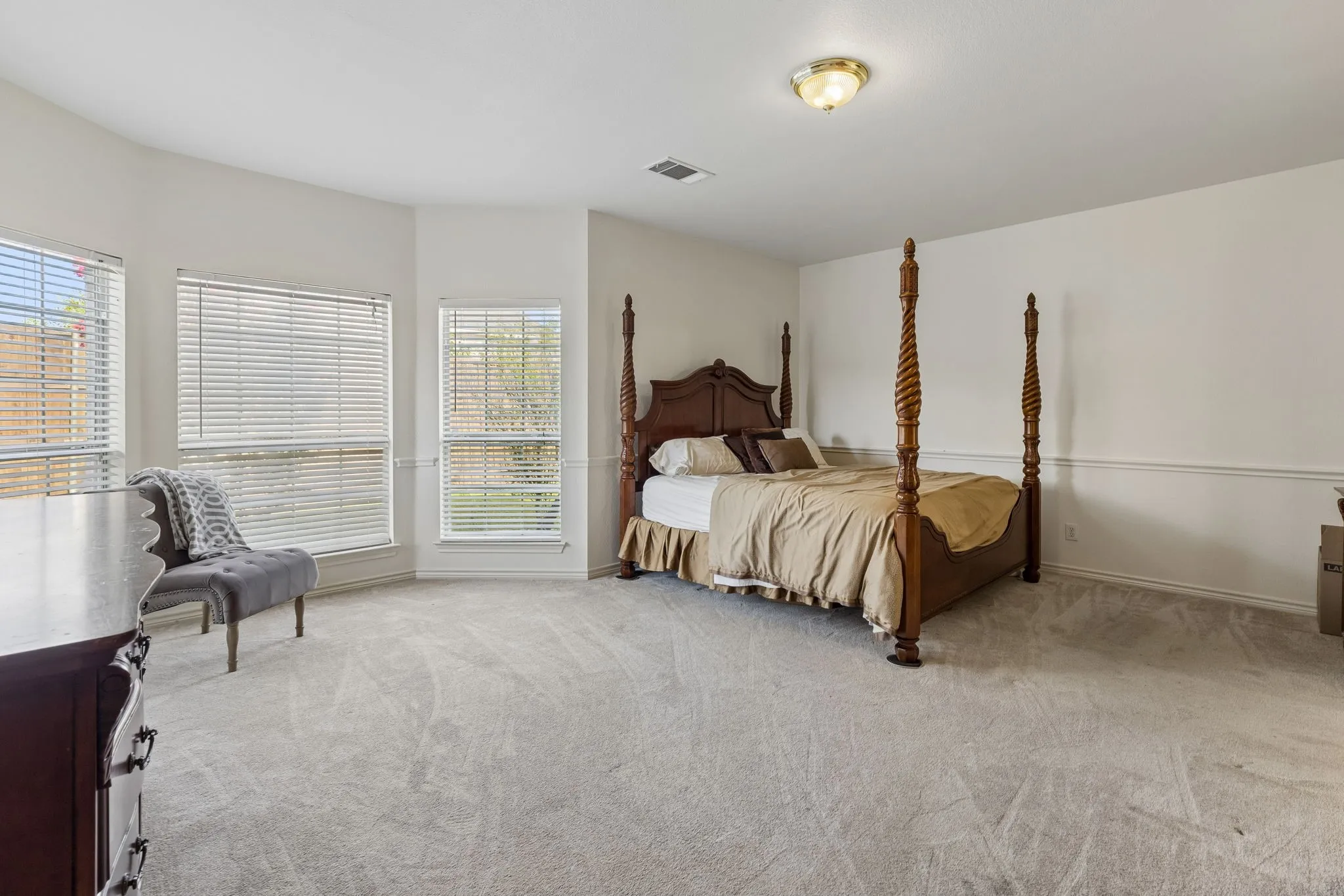 Spacious room featuring light-colored walls and grey carpeting