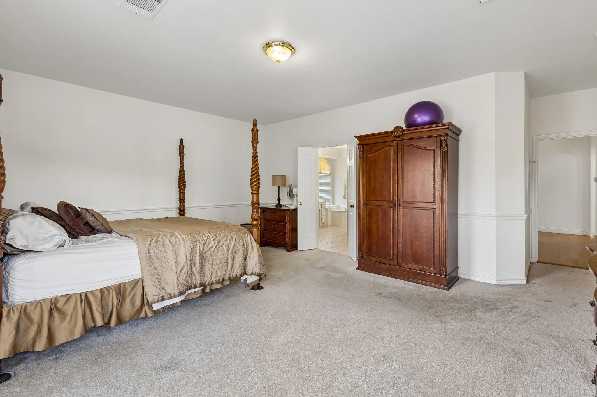 Spacious room featuring light-colored carpeting and white walls with chair rail molding