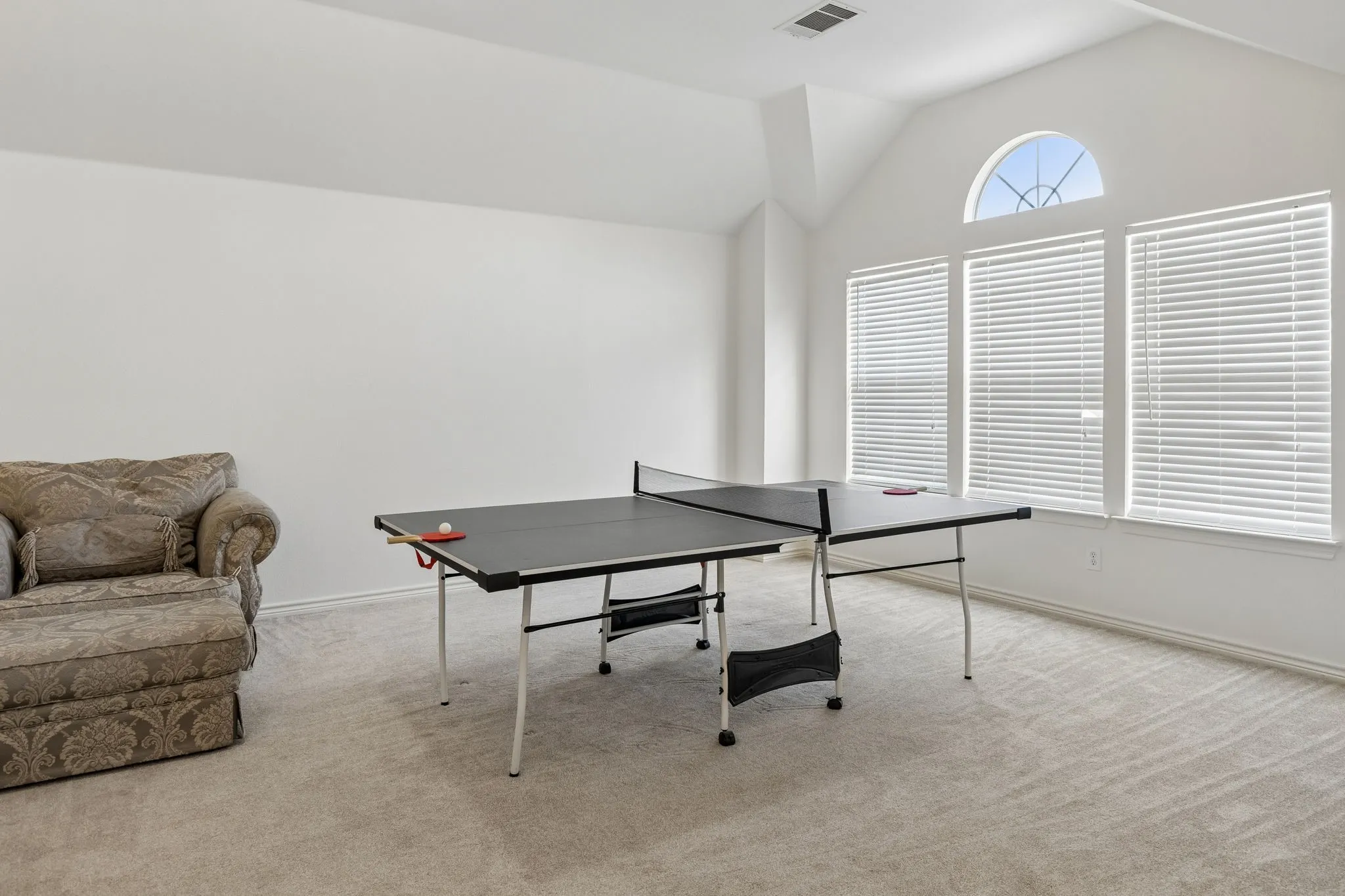 Spacious bonus room featuring carpet flooring, crisp white walls, and a vaulted ceiling