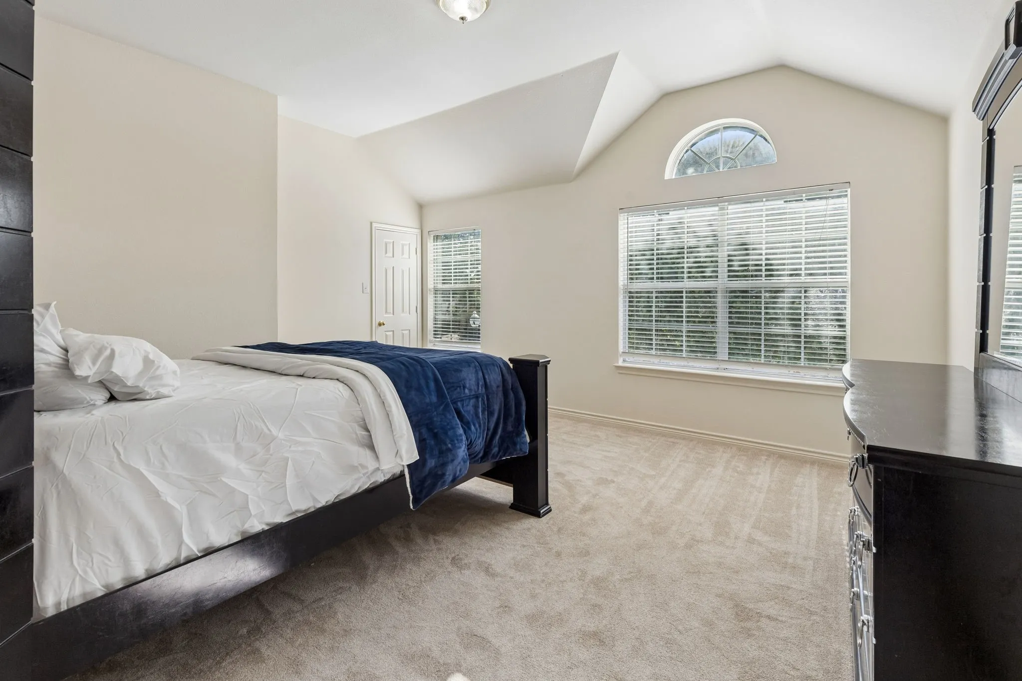 Vaulted ceiling bedroom with a large window and arched transom