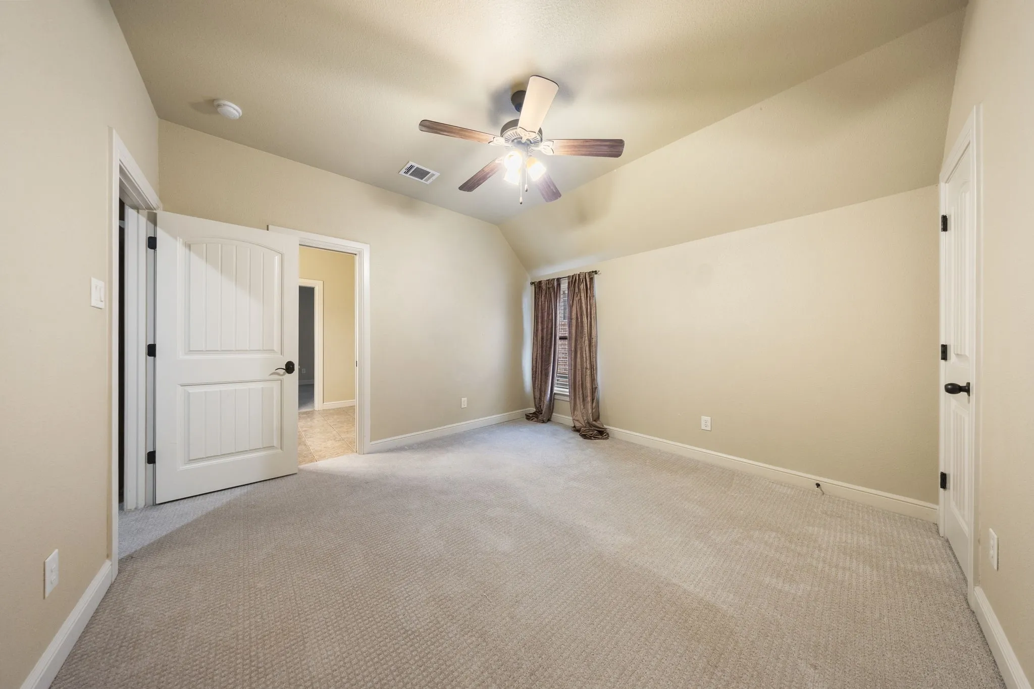 Vaulted ceiling with a ceiling fan, light-toned carpeting, and white paneled doors