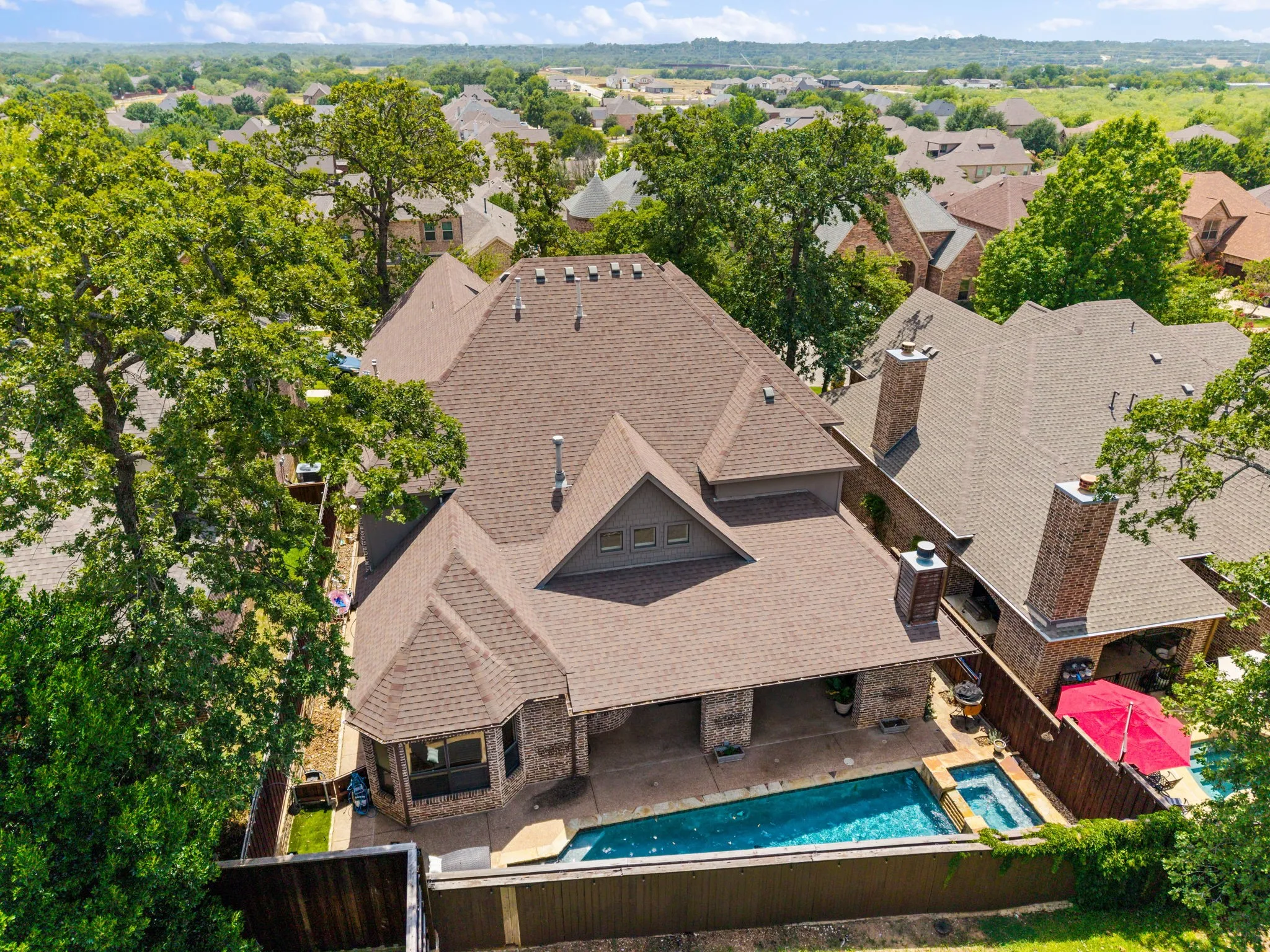 Aerial view showcasing a sophisticated two-story residence with multiple peaked rooflines and dimensional architectural detailing
