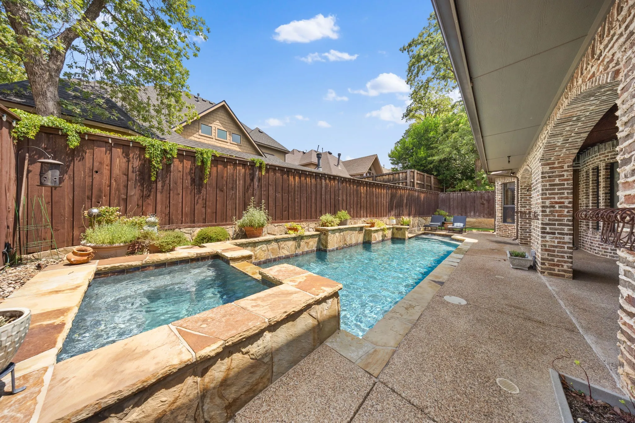 Backyard features a rectangular swimming pool with integrated spa and stone coping