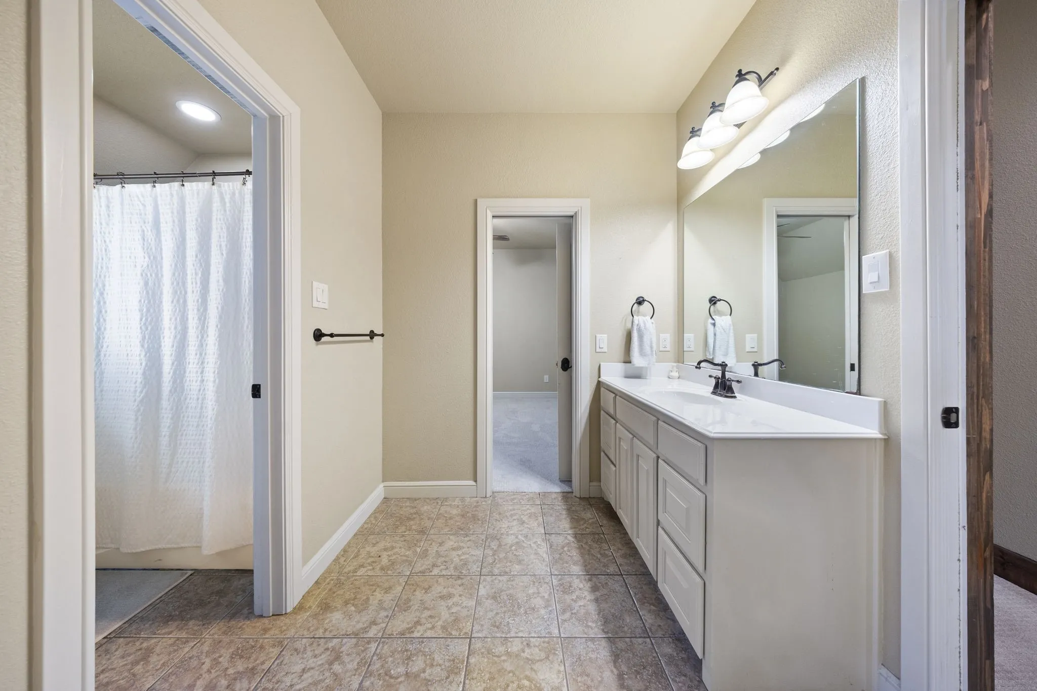 Spa-inspired primary bathroom featuring a spacious layout with dual-sink vanity, white quartz countertop, brushed nickel fixtures, and abundant overhead lighting