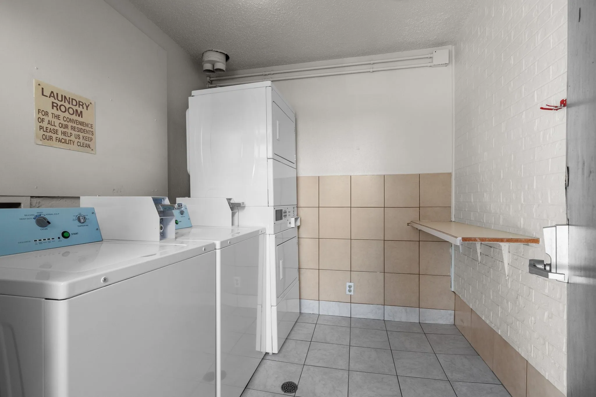 Dedicated laundry area featuring multiple top-load washing machines and stacked dryers