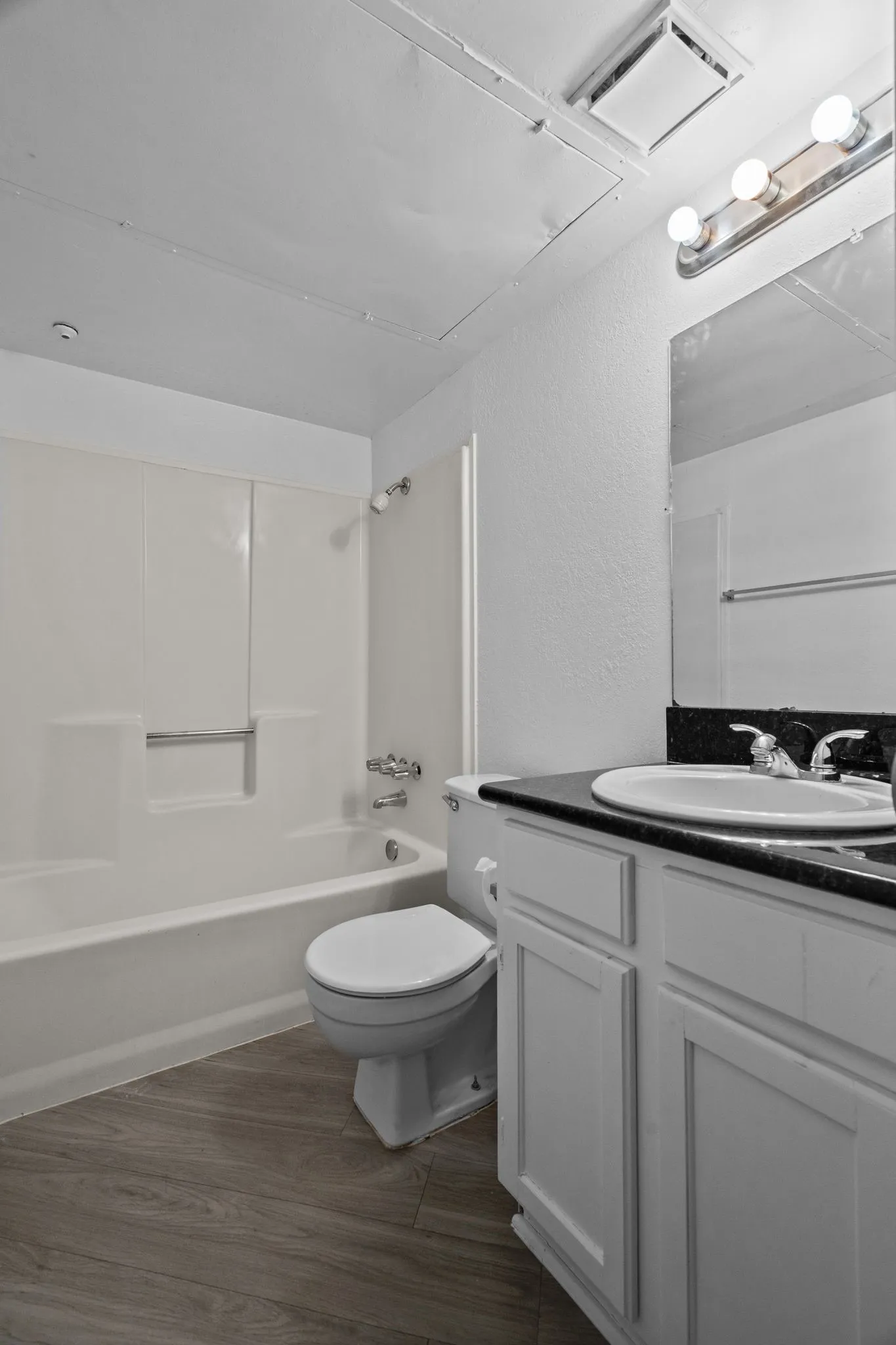 Bathroom featuring a white vanity with panel cabinetry, a black countertop, and an undermount sink
