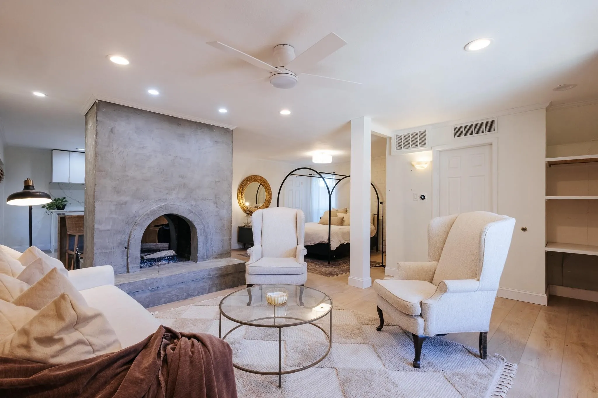 Open-concept living space featuring a textured concrete fireplace, ceiling fan, recessed lighting, and light wood-finish flooring
