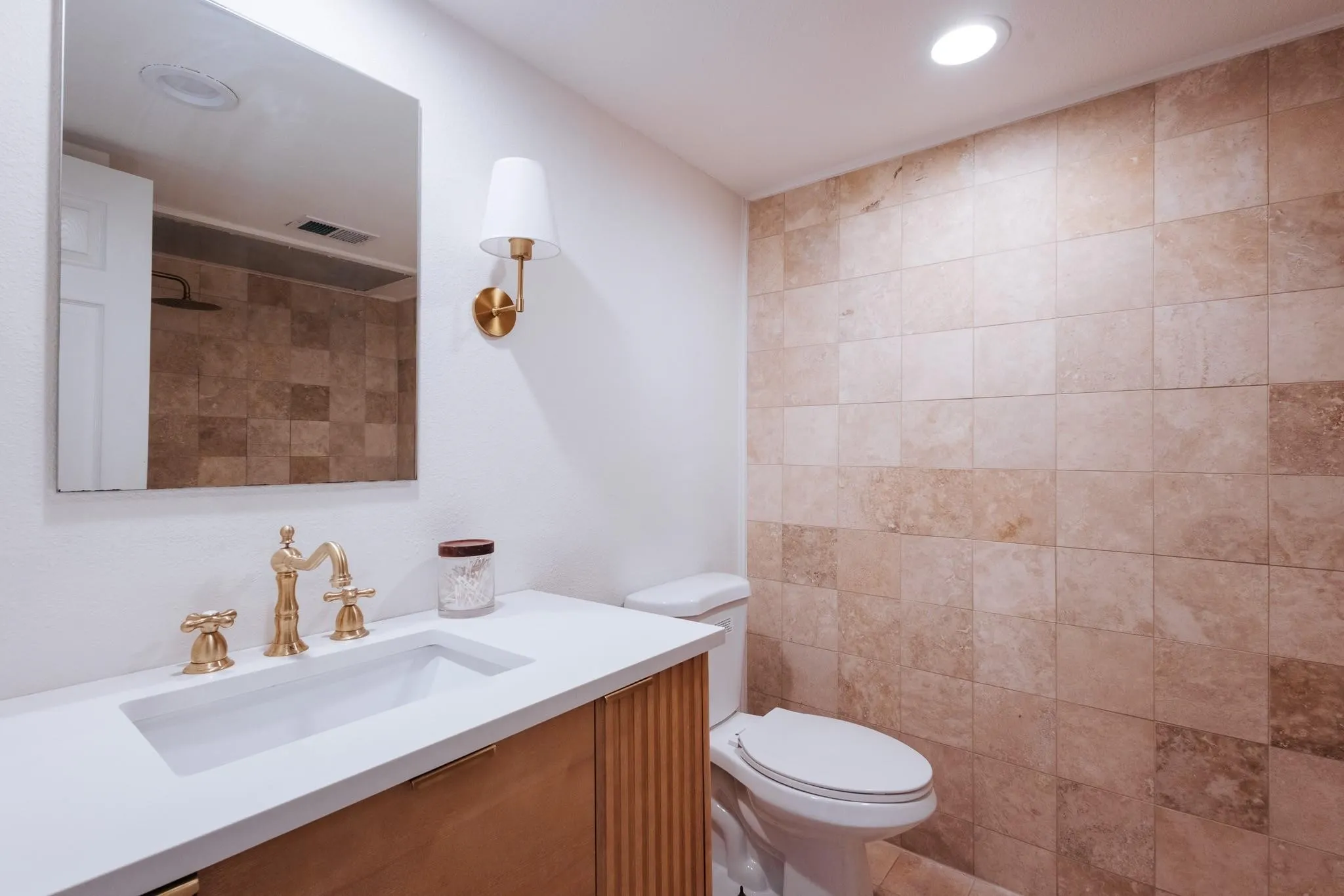 Bathroom featuring a modern vanity with integrated sink, gold-finish fixtures, and a wall-mounted sconce