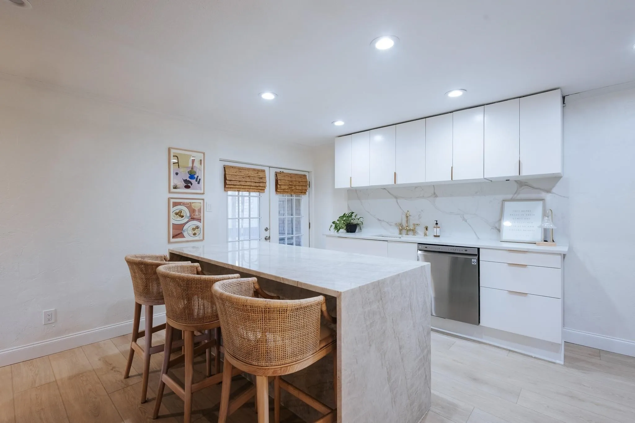Modern kitchen featuring a waterfall island, white cabinetry, a stainless steel dishwasher, integrated sink, and recessed lighting