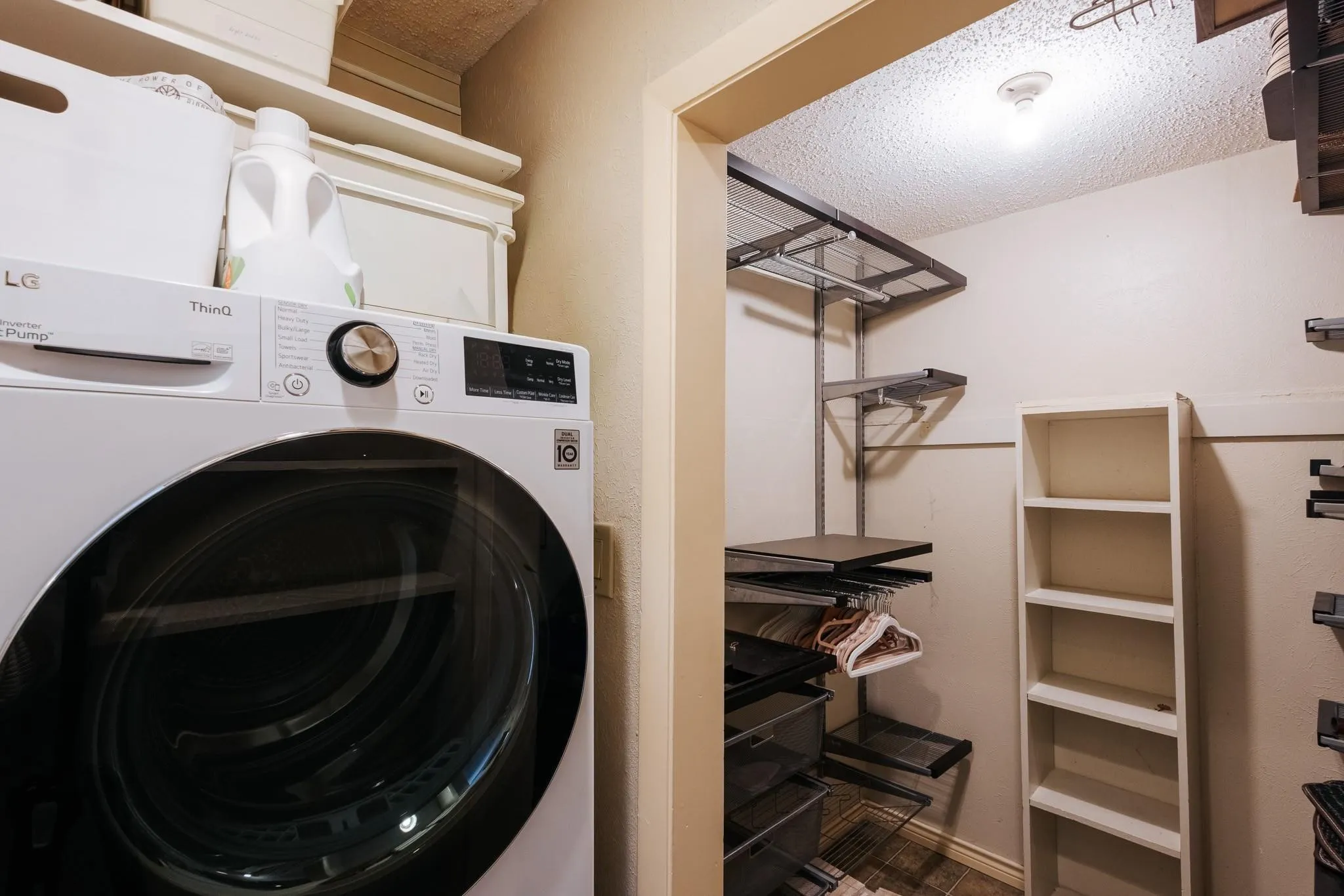 Dedicated laundry area featuring a front-load washer and upper shelving