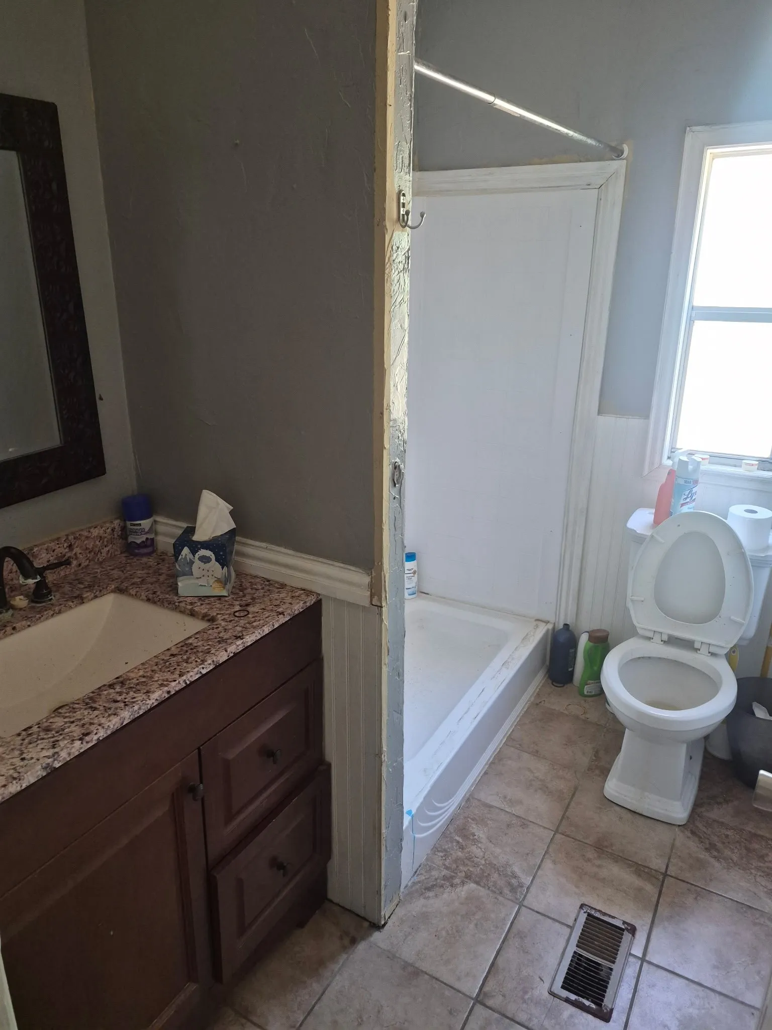 Vanity with granite-style countertop and integrated sink, ceramic tile flooring, and white paneled wainscoting