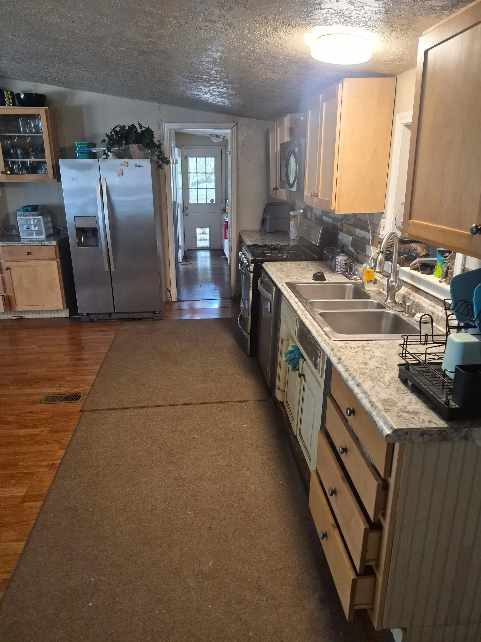 Kitchen featuring wood cabinetry, a stainless steel refrigerator, a double basin sink, and a stone-look countertop