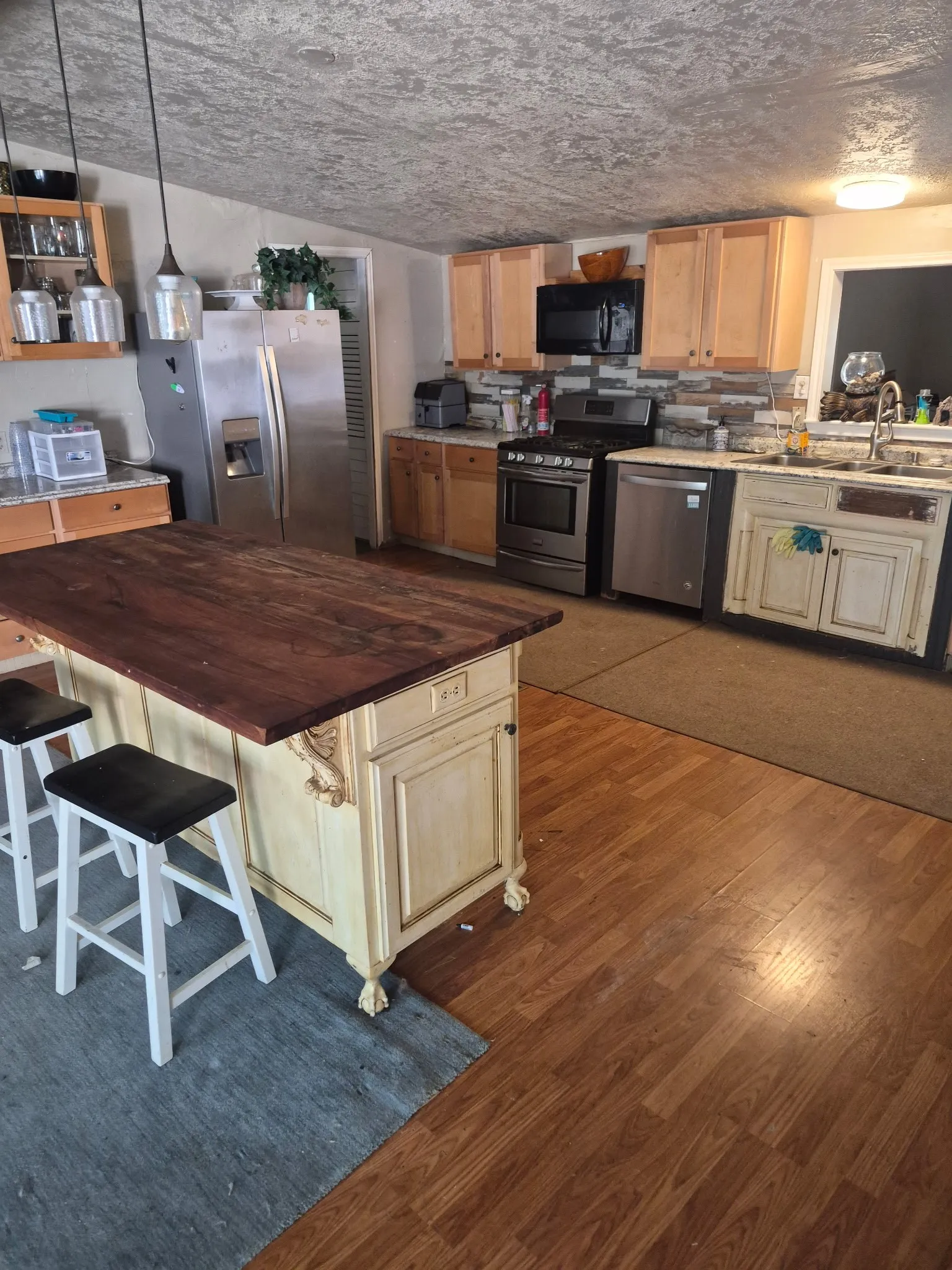 Kitchen featuring wood-finish flooring, a central island with a wood countertop, and stainless steel appliances