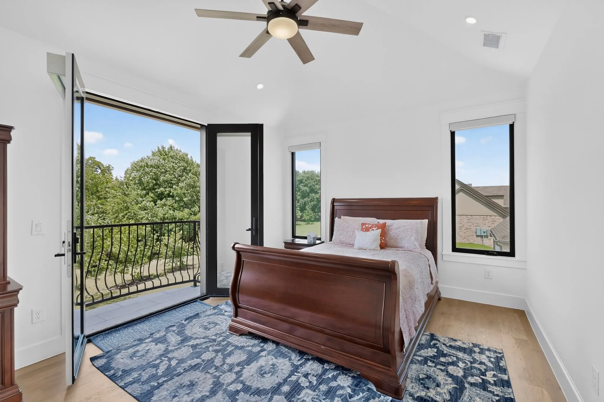 Light wood-finish flooring with crisp white walls, ceiling fan, lots of windows, along with the twin doors opening to the Juliet balcony.