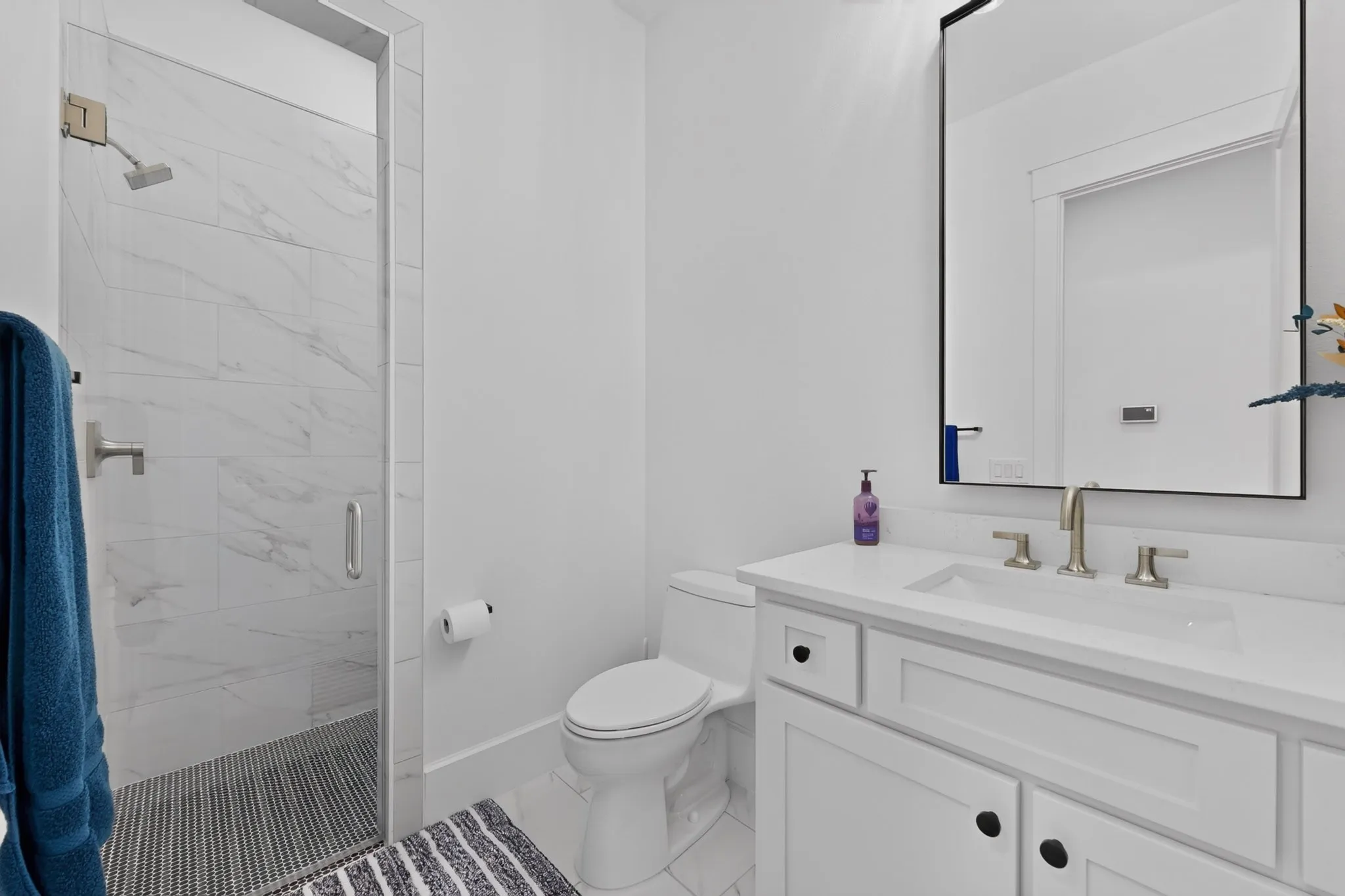 Modern bathroom with a glass-enclosed shower featuring large format tile and a rainfall showerhead