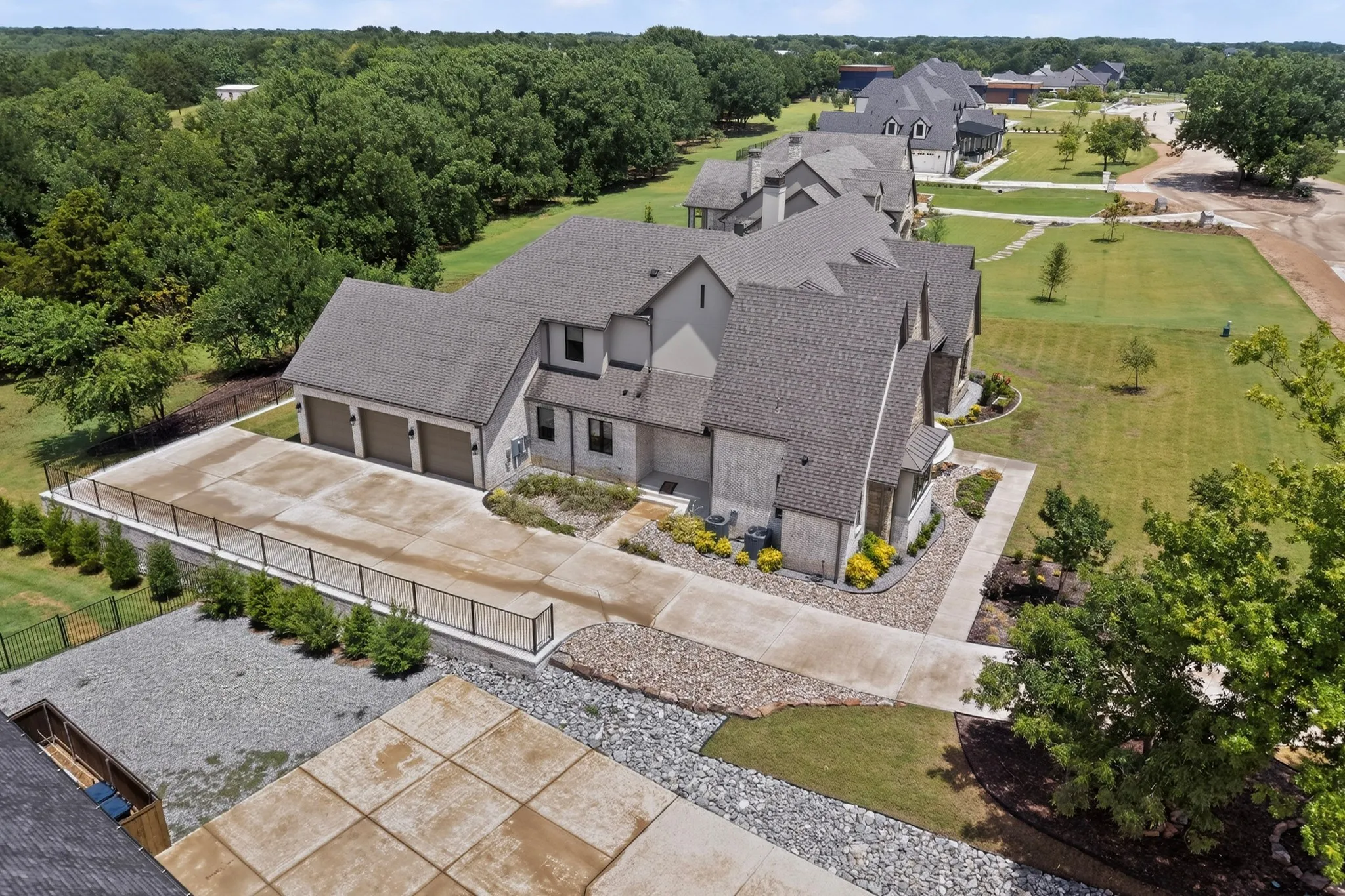Contemporary residence featuring a oversized three-car garage, stone and stucco exterior, and a large concrete driveway