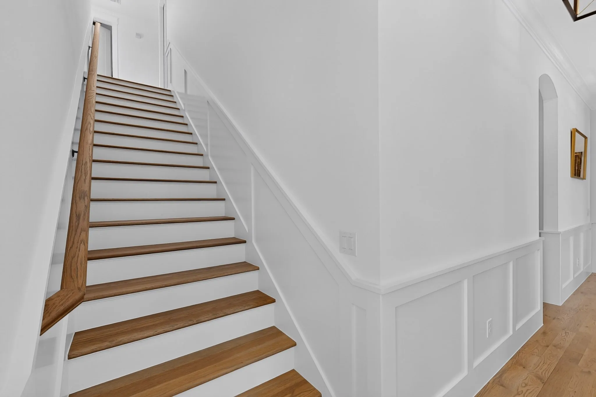 Staircase featuring solid wood-finish treads and risers, a wood handrail, and wainscoting invite you to view the Upstairs Bedroom & Bath (with the Juliet balcony)!