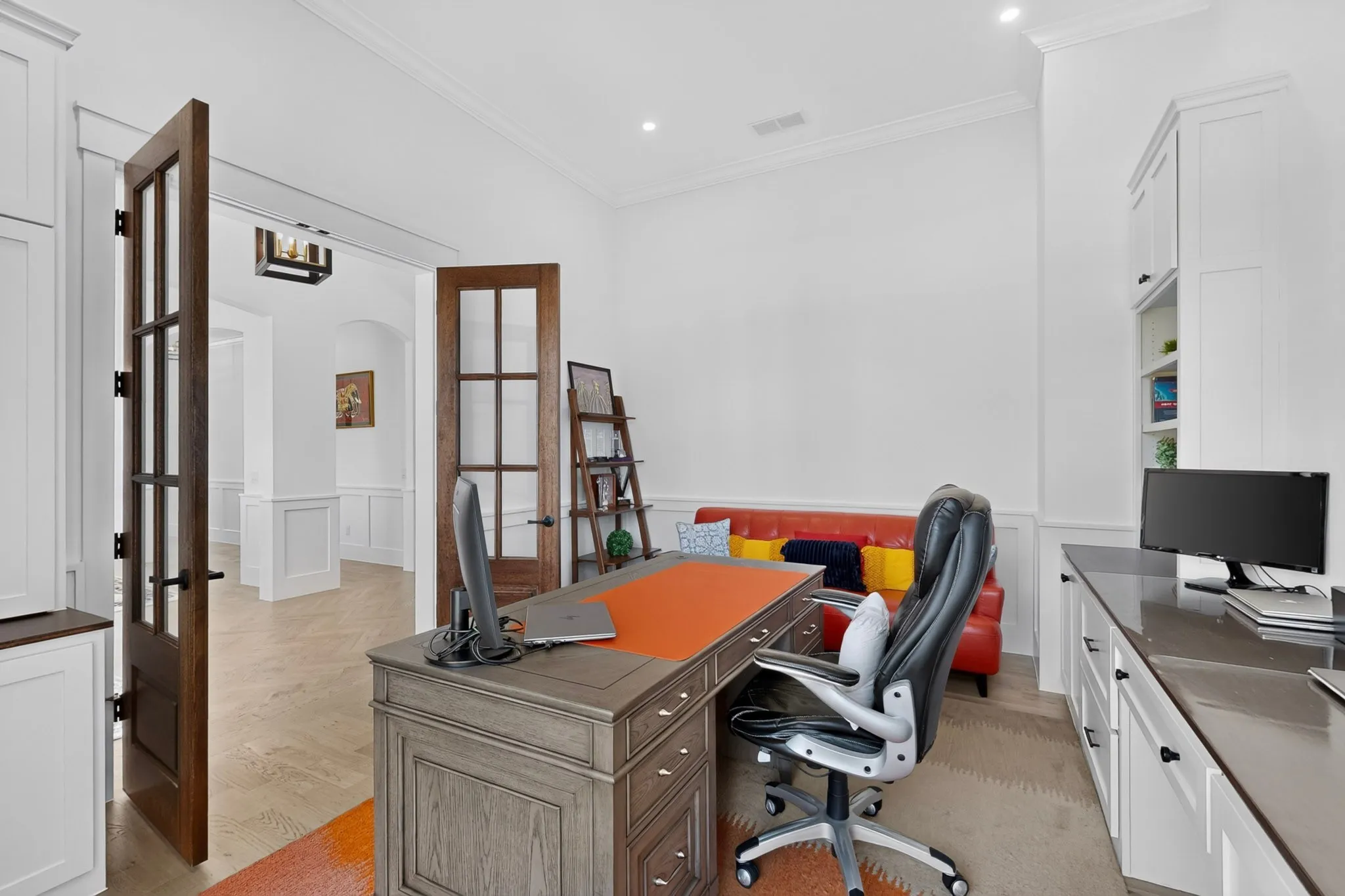 Office space featuring wood-finish flooring, wainscoting, and crown molding